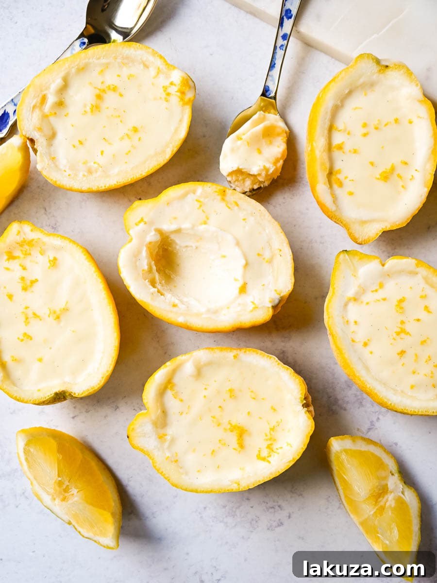 Close-up of three individual lemon possets in clear glass ramekins, highlighting the smooth, creamy texture and a subtle garnish of lemon zest.