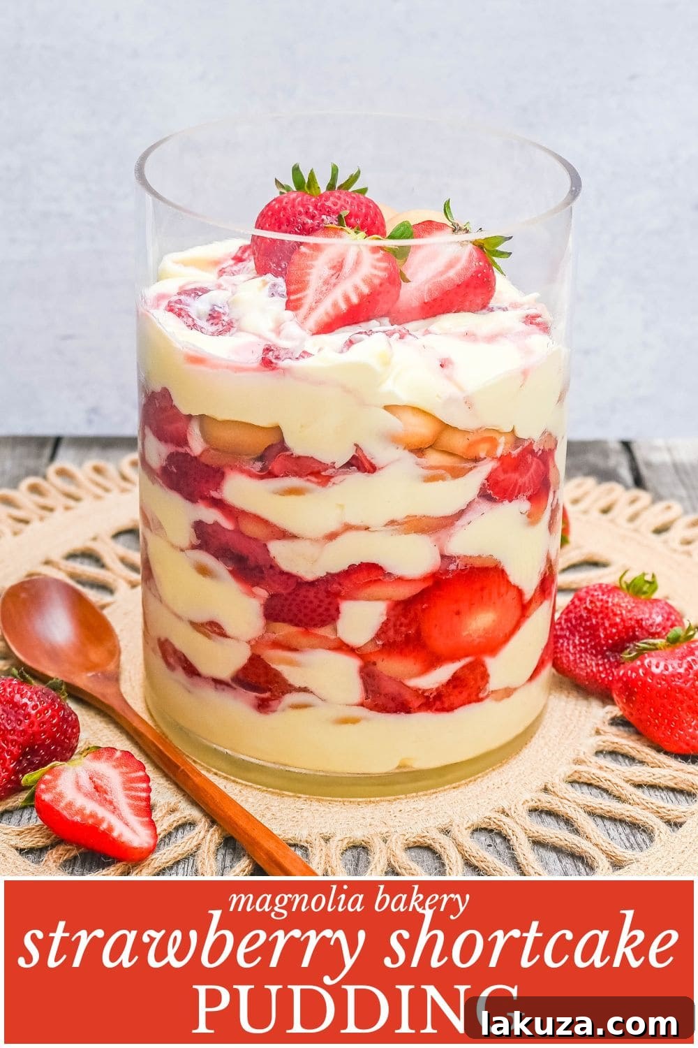 Vertical shot of Magnolia Bakery Strawberry Shortcake Pudding in a glass jar, garnished with fresh berries and a Nilla wafer.