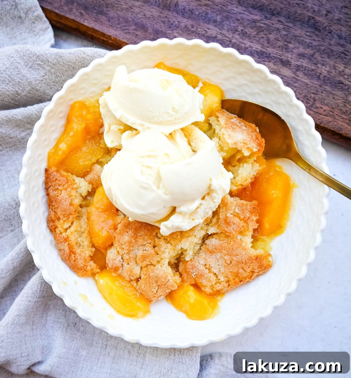 A generous serving of homemade nectarine cobbler in a bowl, topped with a scoop of creamy vanilla ice cream.