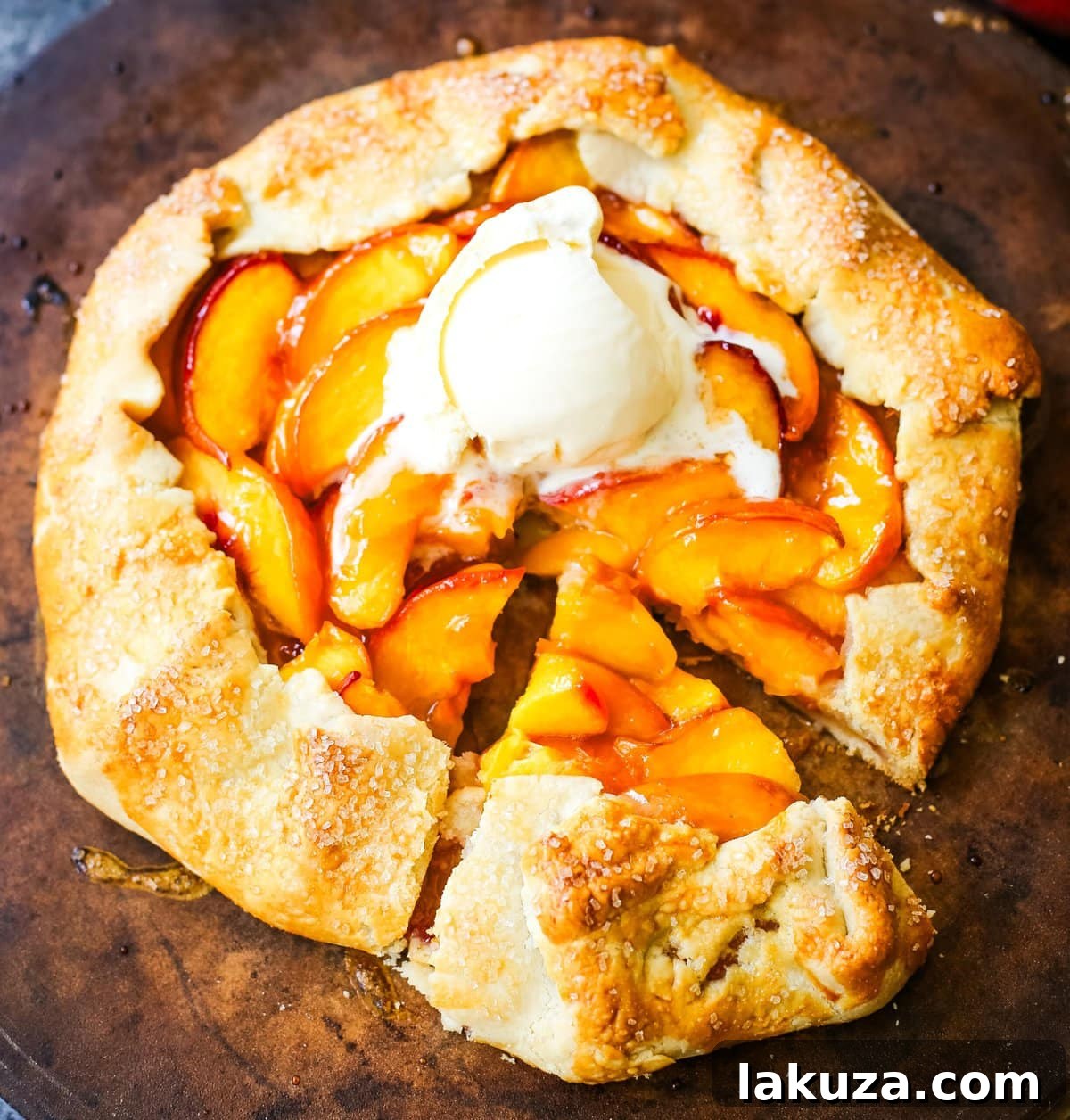 Sliced peaches arranged artfully in a free-form galette crust on a parchment-lined baking sheet, prepared for baking.
