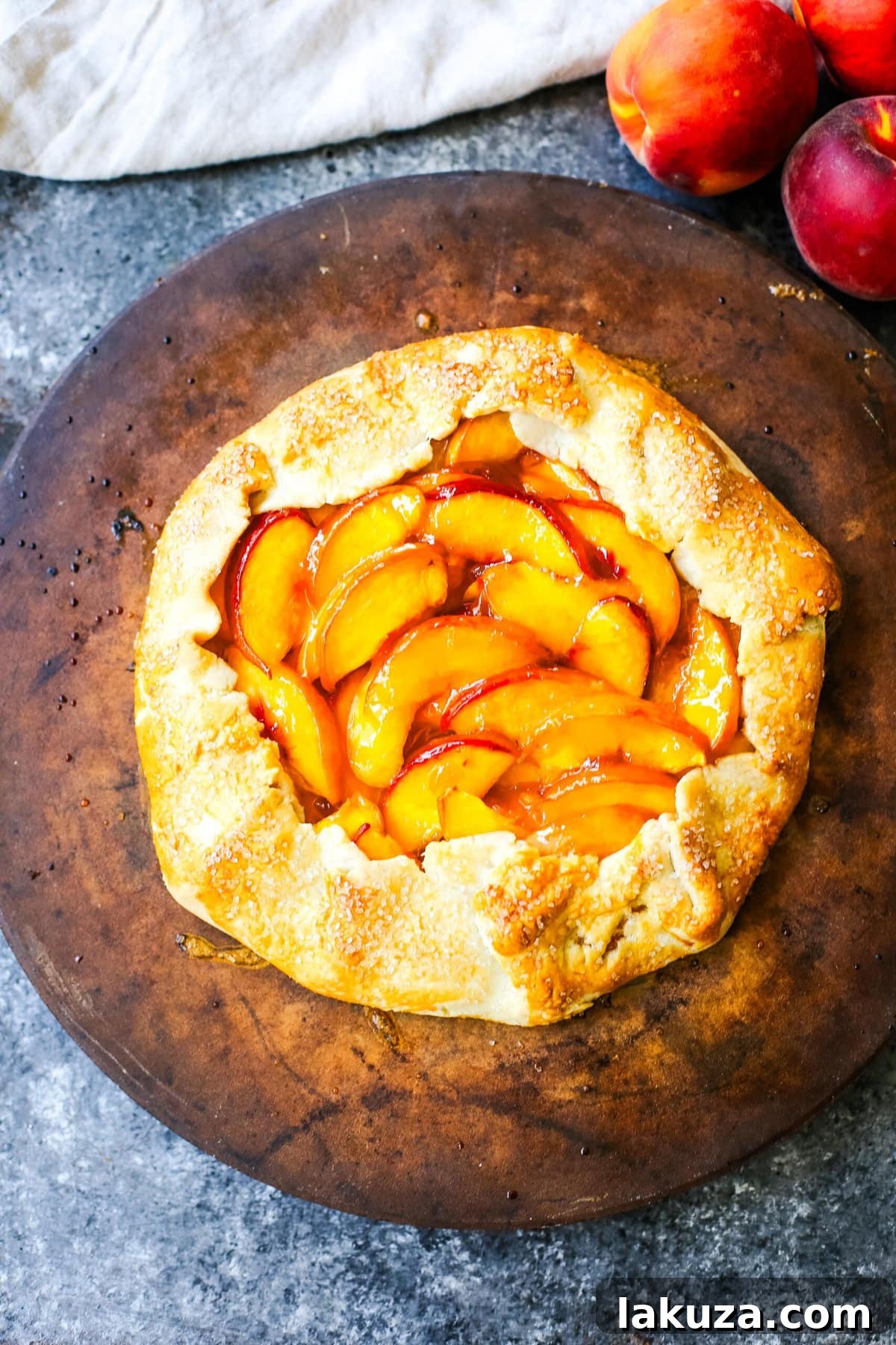 Arranging fresh, sliced peaches onto the rolled-out galette dough on a parchment-lined baking sheet, leaving a defined border for folding.
