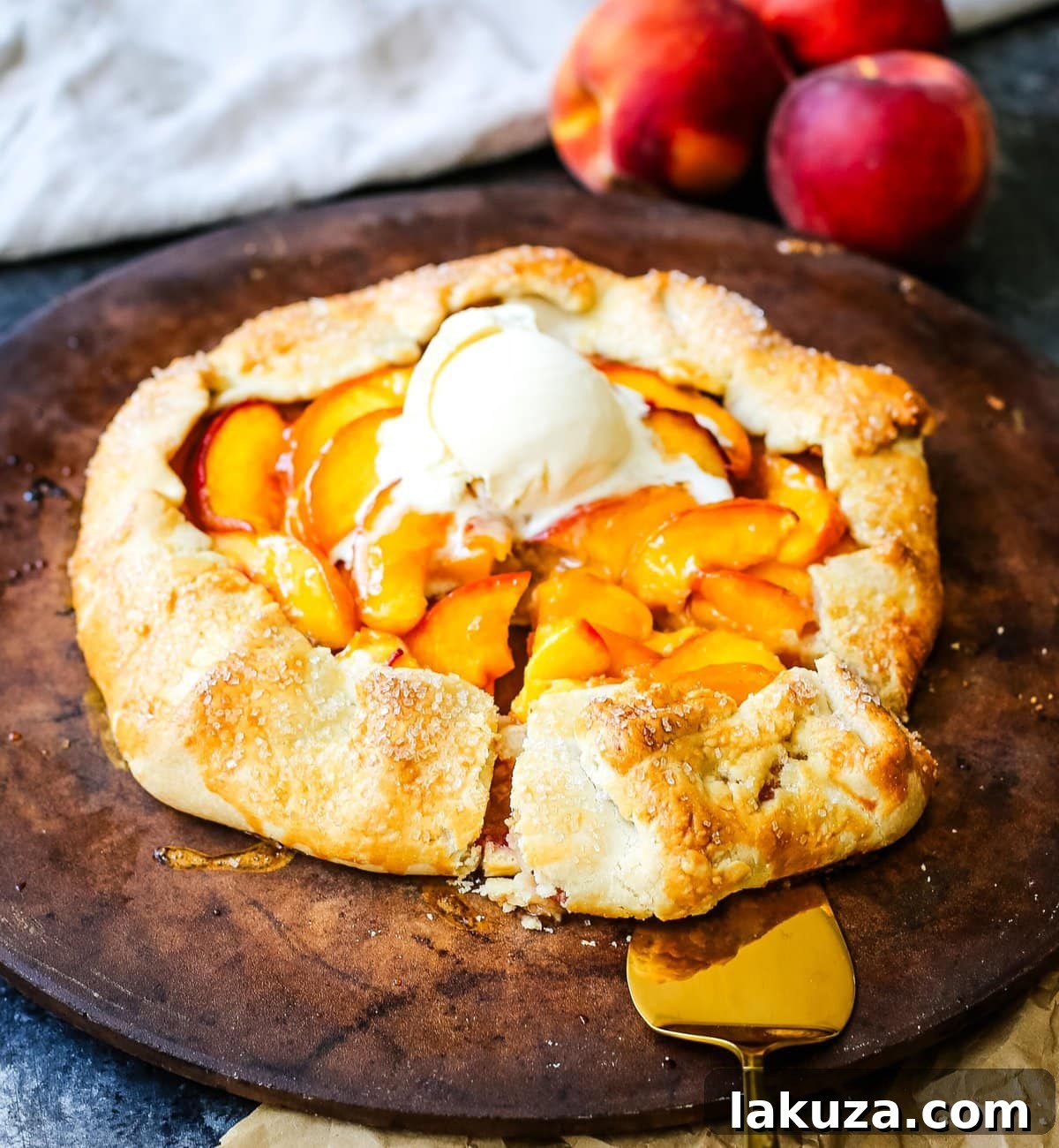A baked Homemade Peach Galette, still warm and featuring a glossy jam glaze, is presented on a cooling rack, ready to be served with vanilla ice cream.