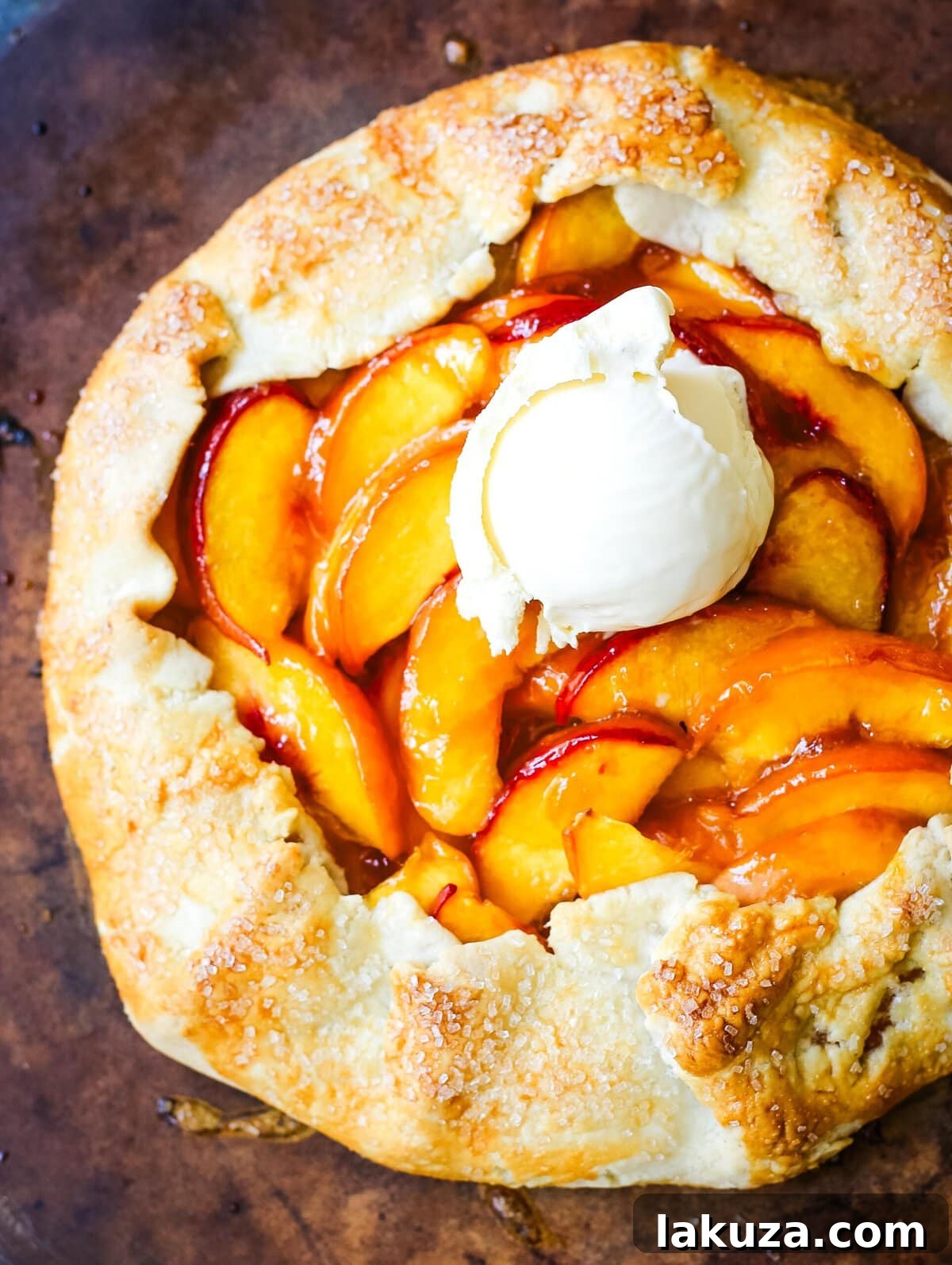 A delectable slice of warm Homemade Peach Galette, perfectly paired with a melting scoop of creamy vanilla ice cream, on a serving plate.