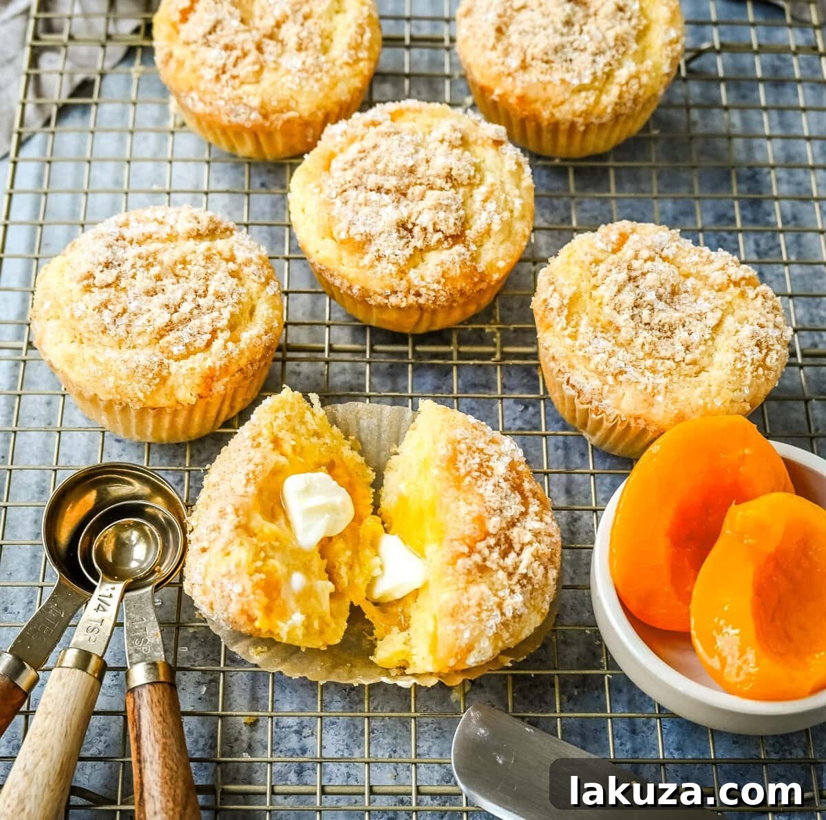 A batch of baked Peach Cobbler Muffins cooling on a wire rack.