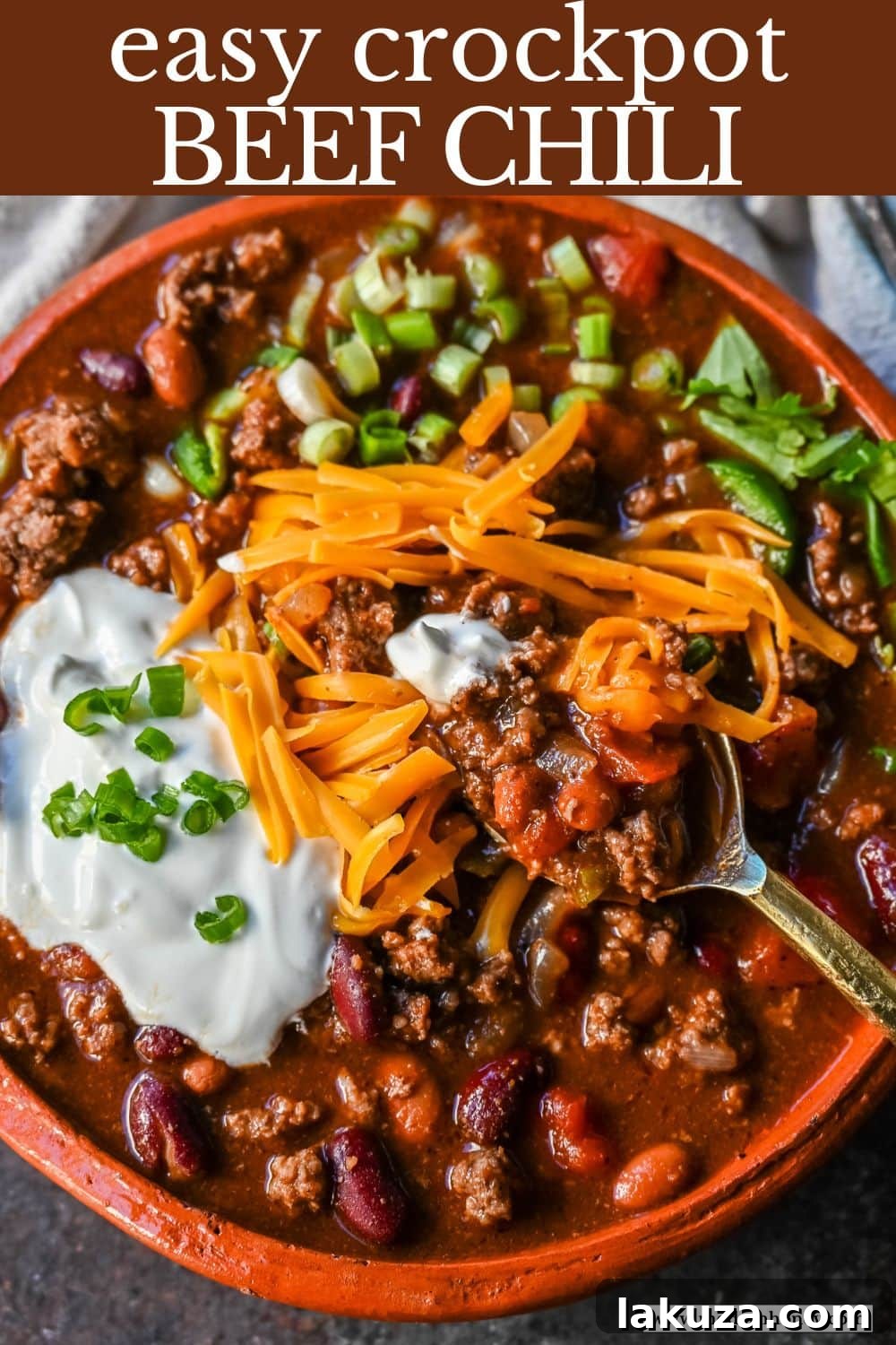 A top-down view of a generously topped bowl of Crockpot Beef Chili, ready to serve.