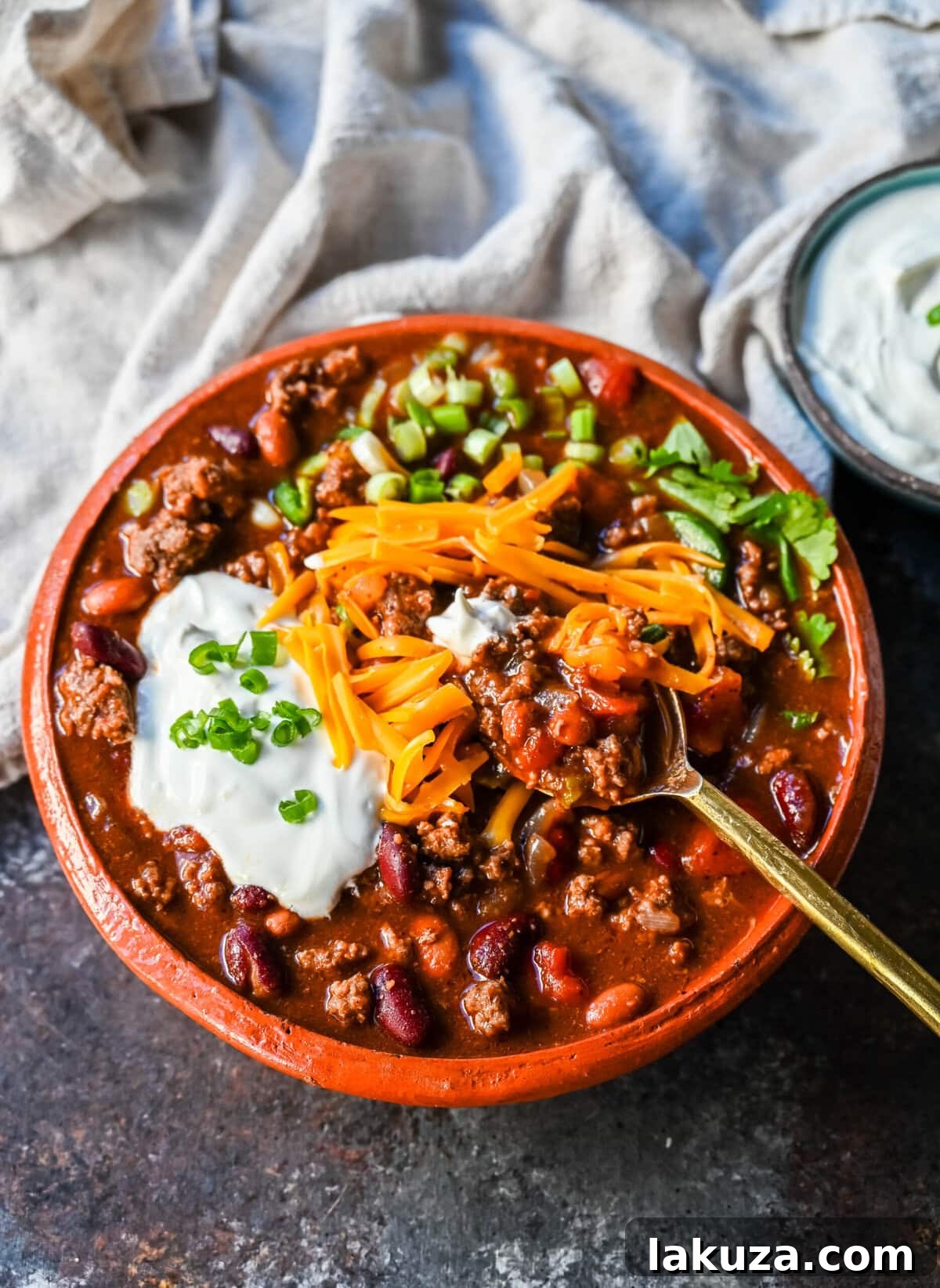 A bowl of slow cooker beef chili, topped with a generous amount of shredded cheese, ready to be enjoyed.