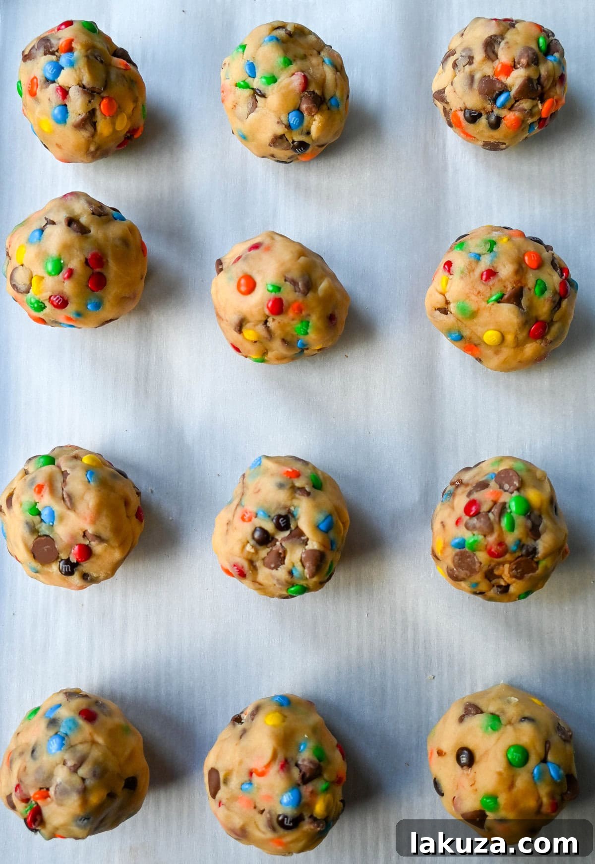 M&M Nutella Volcano Cookies 6 Unbaked M&M Nutella Lava Cookie dough balls with visible M&M's on a cookie sheet.