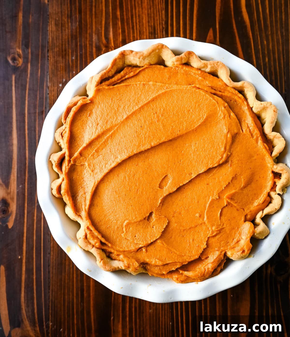 Golden Harvest Hillys Pumpkin Caramel Pie 12 Pumpkin ganache being poured into the pie crust over the caramel layer.