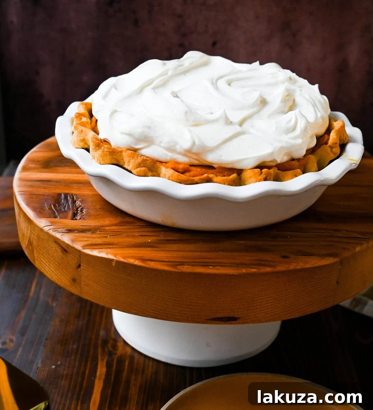 Golden Harvest Hillys Pumpkin Caramel Pie 4 Milk Bar's Pumpkin Caramel Pie with a generous dollop of whipped cream and streusel, showcasing its inviting texture.