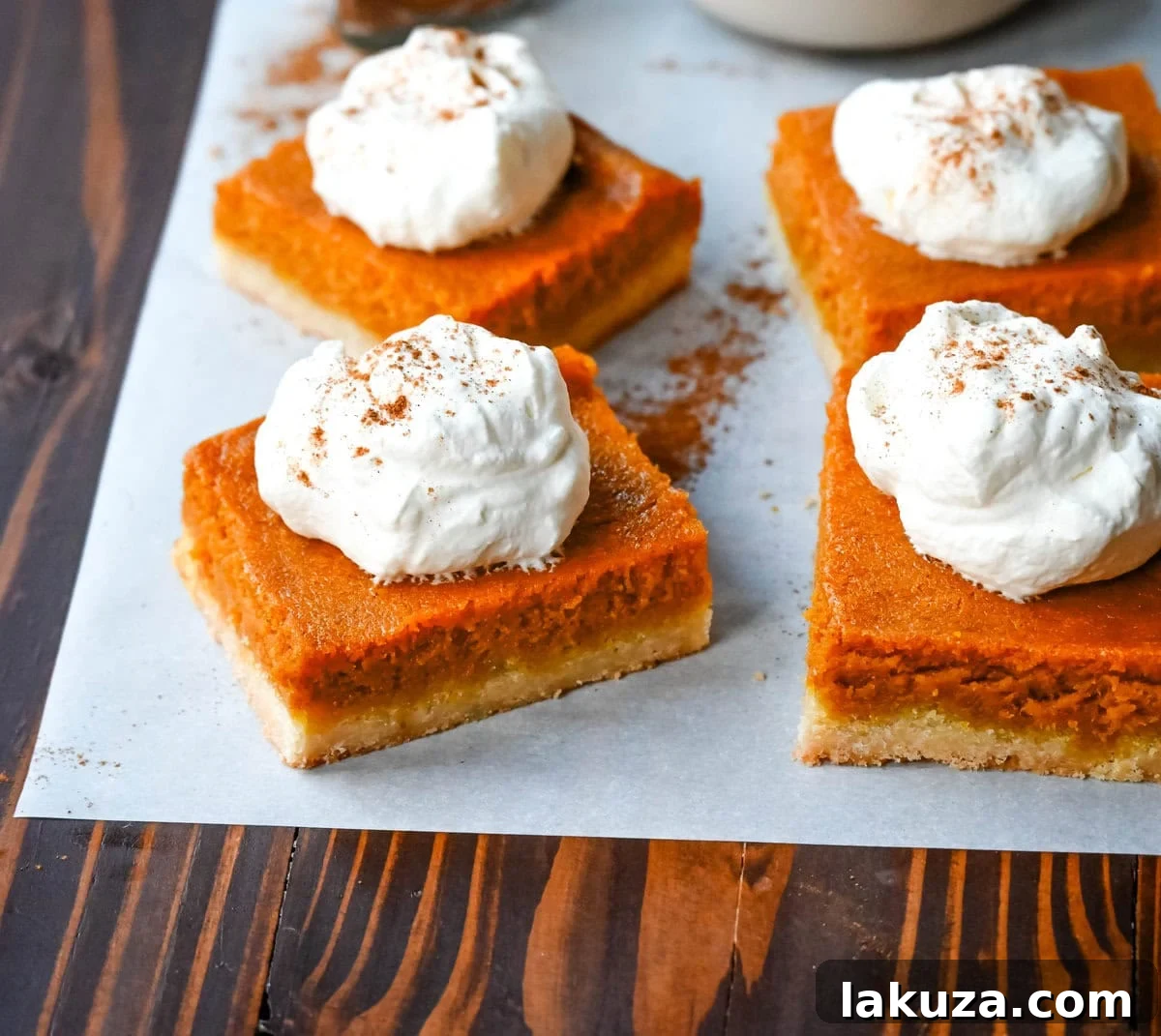 Delicious homemade pumpkin pie bars with a creamy filling and a shortbread crust, topped with whipped cream, ready to be served.