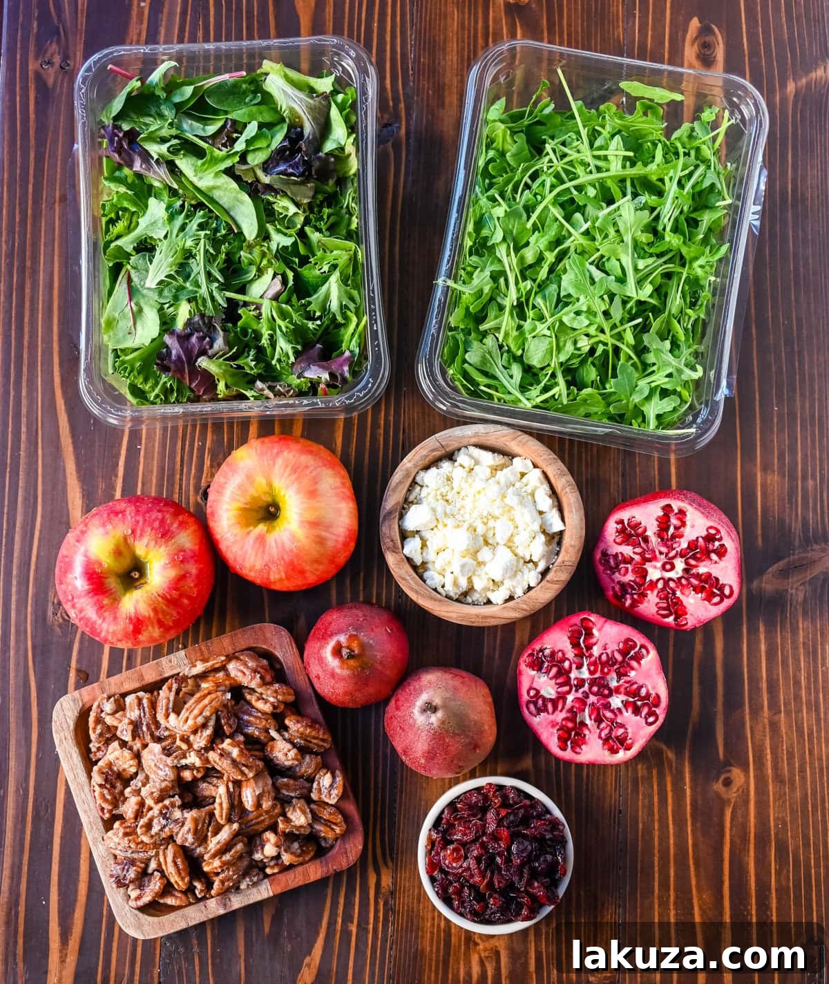 Ingredients for an Autumn Honeycrisp Apple and Candied Pecan Salad. Includes spring mix, honeycrisp apples, Anjou pears, pomegranate seeds, dried cranberries, feta or goat cheese, and ingredients for a maple dressing.