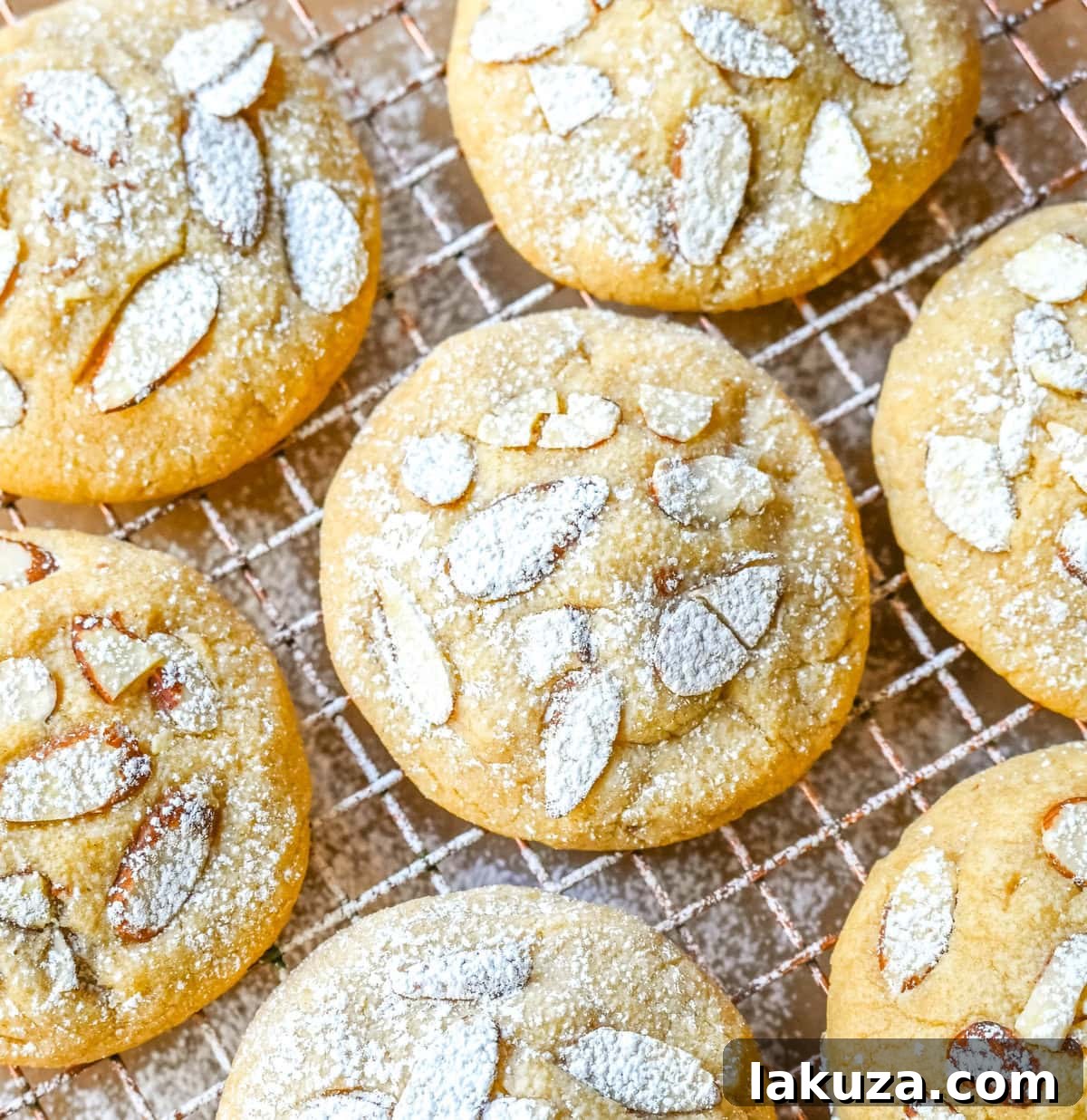 Almond Croissant-Inspired Cookies 2 Buttery Almond Croissant Cookies on a baking sheet, showcasing their golden crust and sliced almond topping.