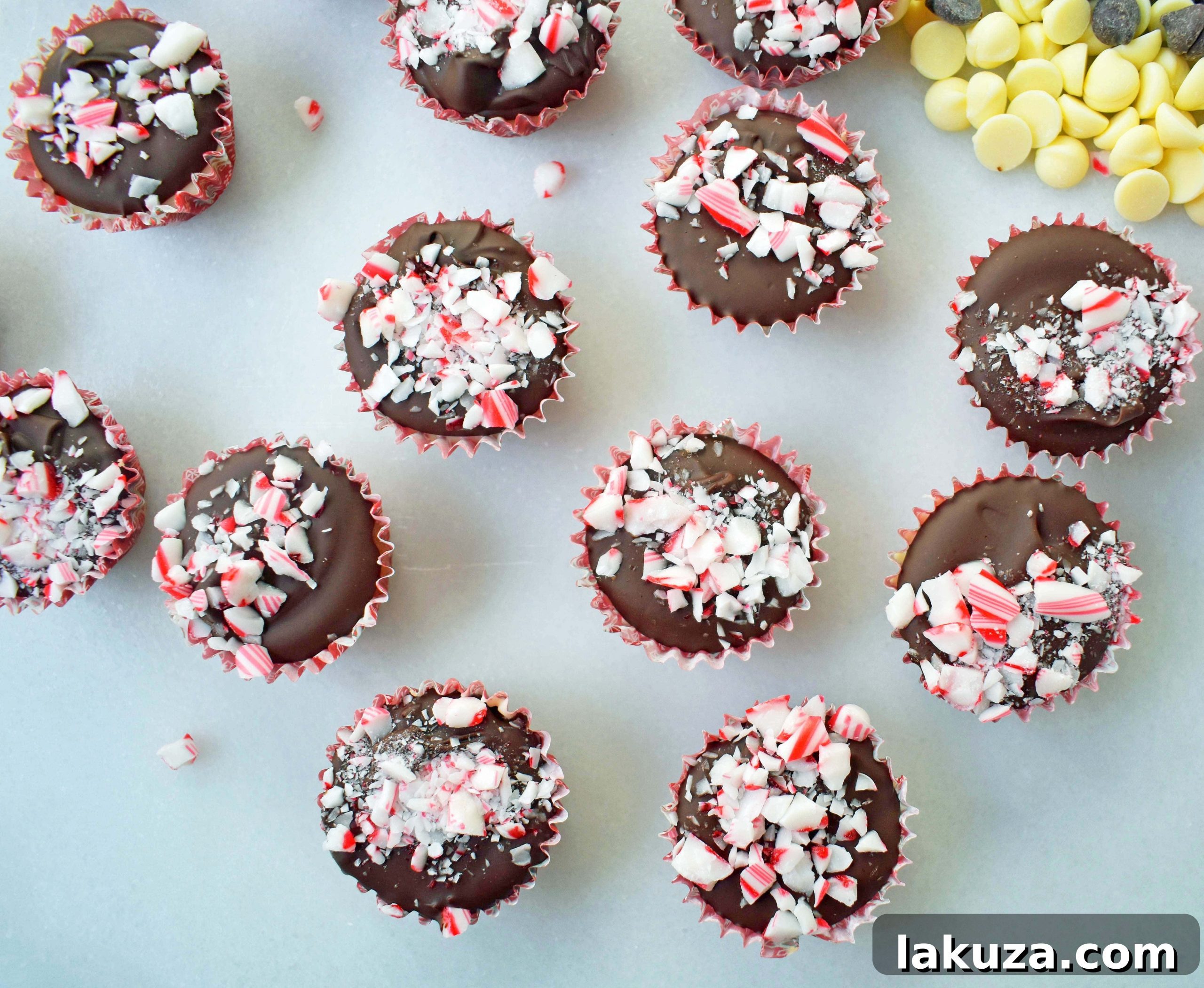 Close-up of a Peppermint Bark Cookie Dough Cup, showing layers of chocolate chip cookie dough, white chocolate, and milk chocolate, garnished with crushed candy canes.