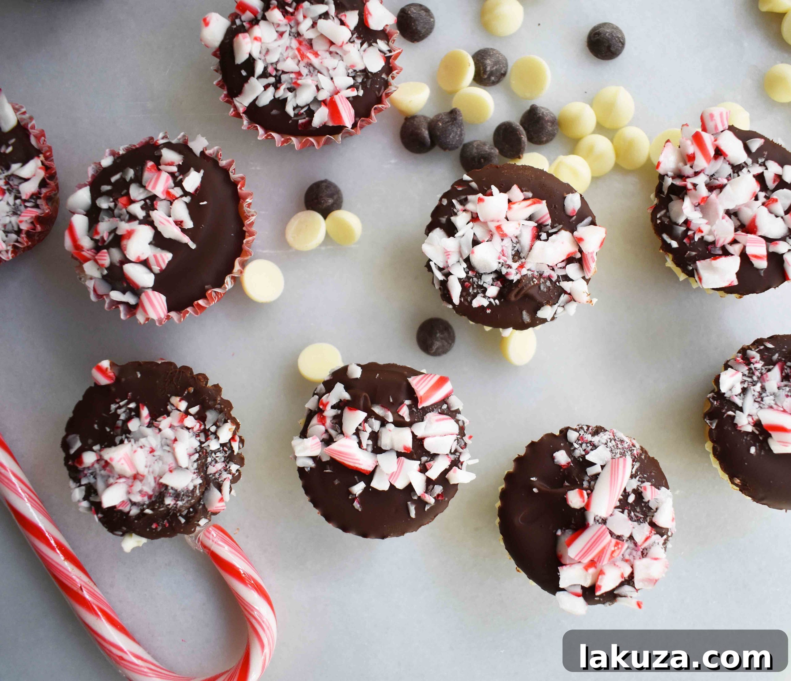 A top-down view of Peppermint Bark Cookie Dough Cups in mini liners, showing the intricate layers and vibrant candy cane topping.