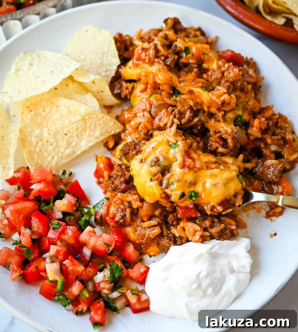 Close-up of a bubbling Cheesy Taco Rice Skillet, showing the rich, red sauce, seasoned ground beef, and grains of rice simmering before the cheese topping is added.