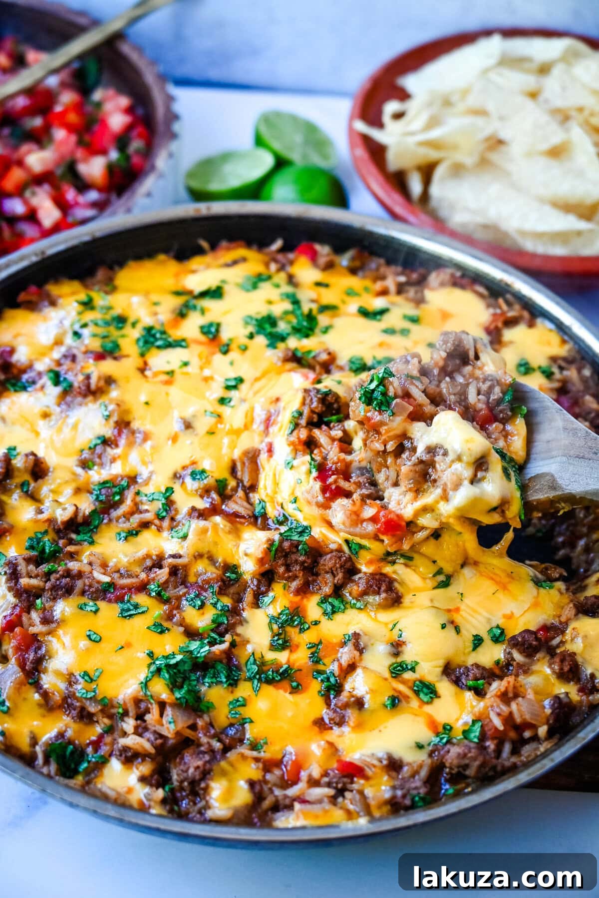 Overhead shot of the Cheesy Taco Rice Skillet, garnished with fresh cilantro and a dollop of sour cream, served directly in the large cast-iron skillet, ready to be enjoyed.