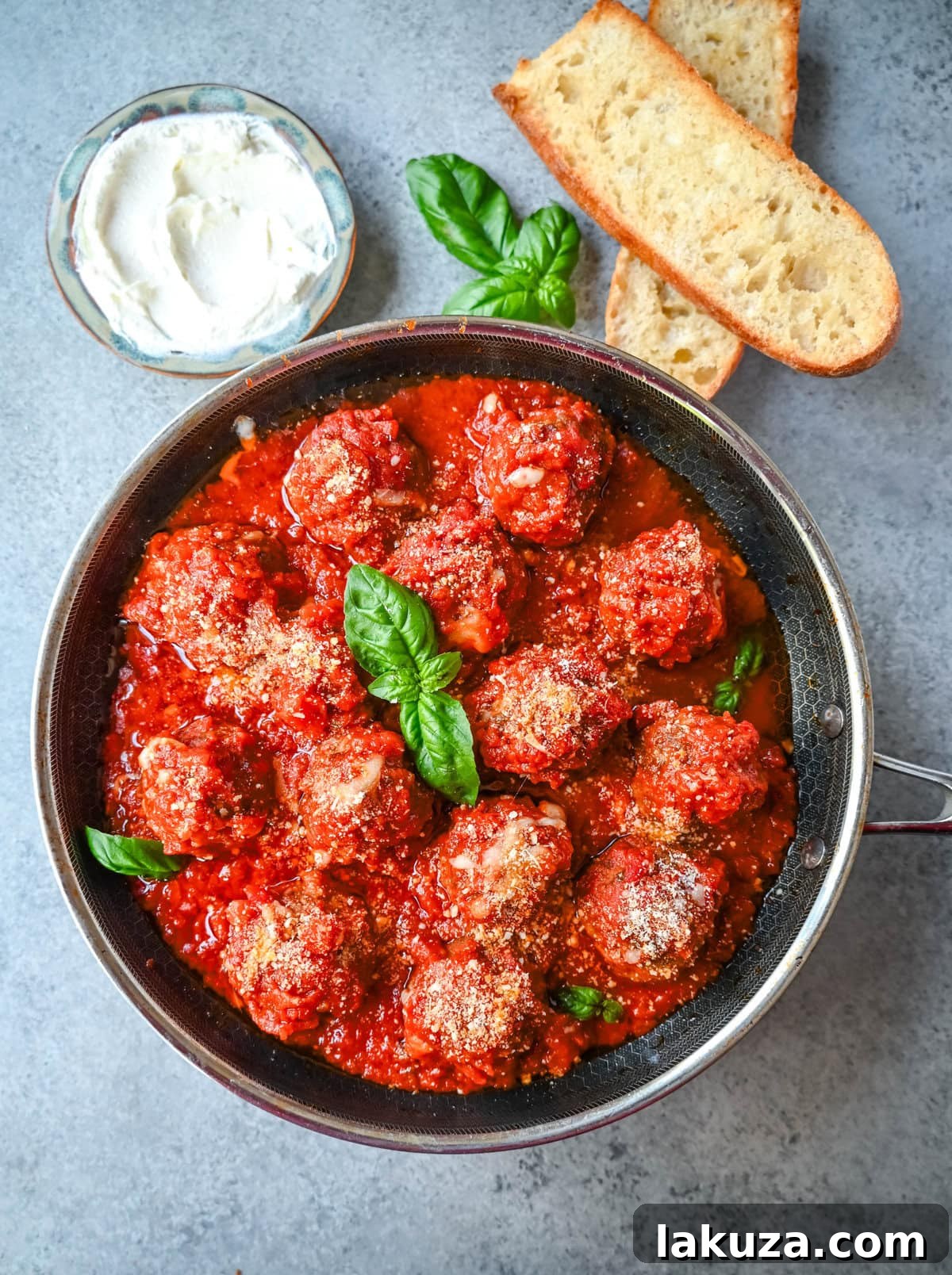 A top-down view of a serving of Ricotta Parmesan Meatballs with pasta and fresh basil, ready to eat.