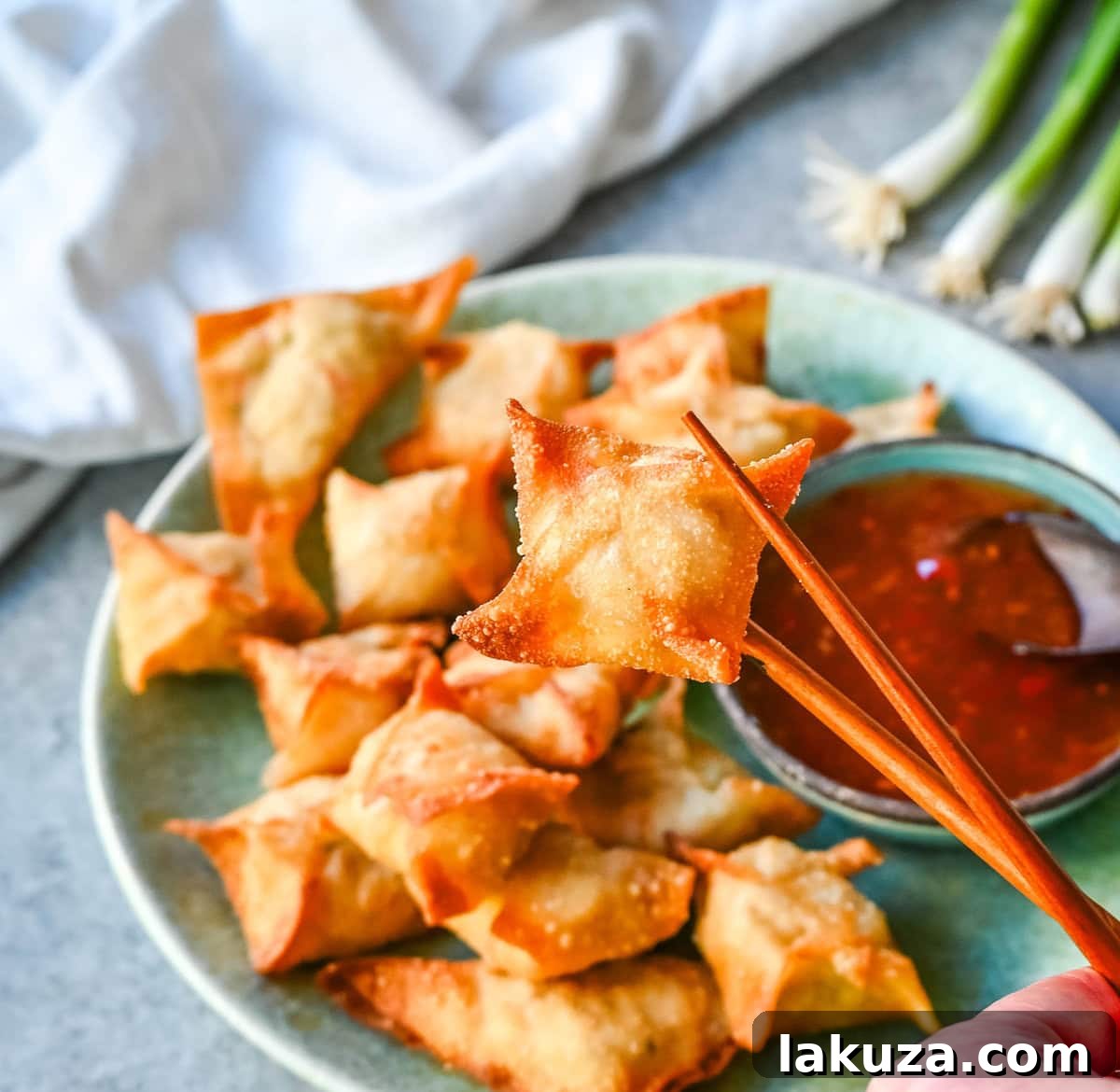 Delicious and crispy golden-fried Crab Rangoons served hot, ready to be dipped in sweet chili sauce.