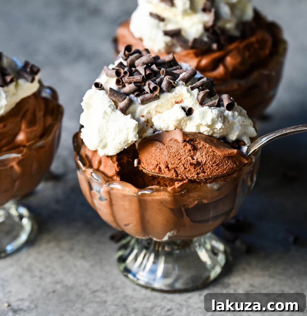 A close-up shot of a rich and decadent chocolate mousse served in a glass, topped with fresh whipped cream and chocolate shavings. The texture is light and airy, promising a delightful dessert experience.