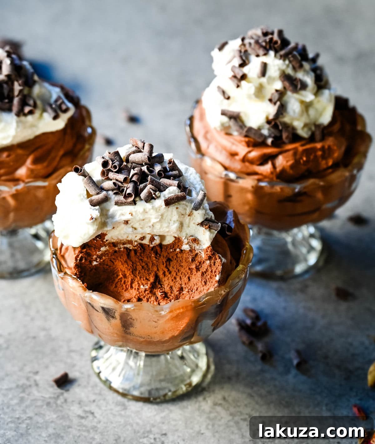 Two individual servings of homemade chocolate mousse, garnished with whipped cream and chocolate curls, presented beautifully in dessert glasses.