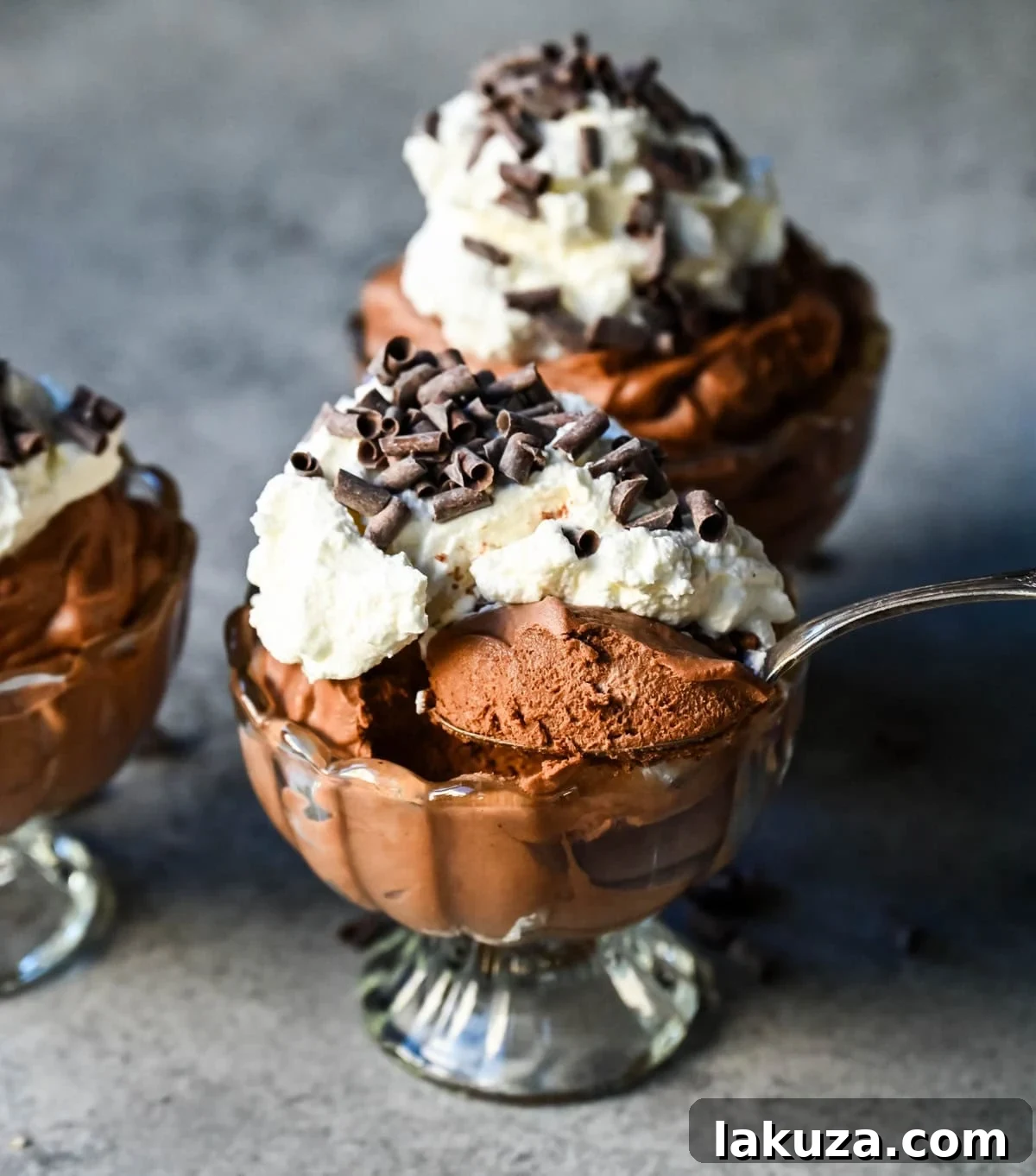 Several servings of chocolate mousse, beautifully garnished with fresh raspberries and chocolate shavings, ready to be enjoyed.