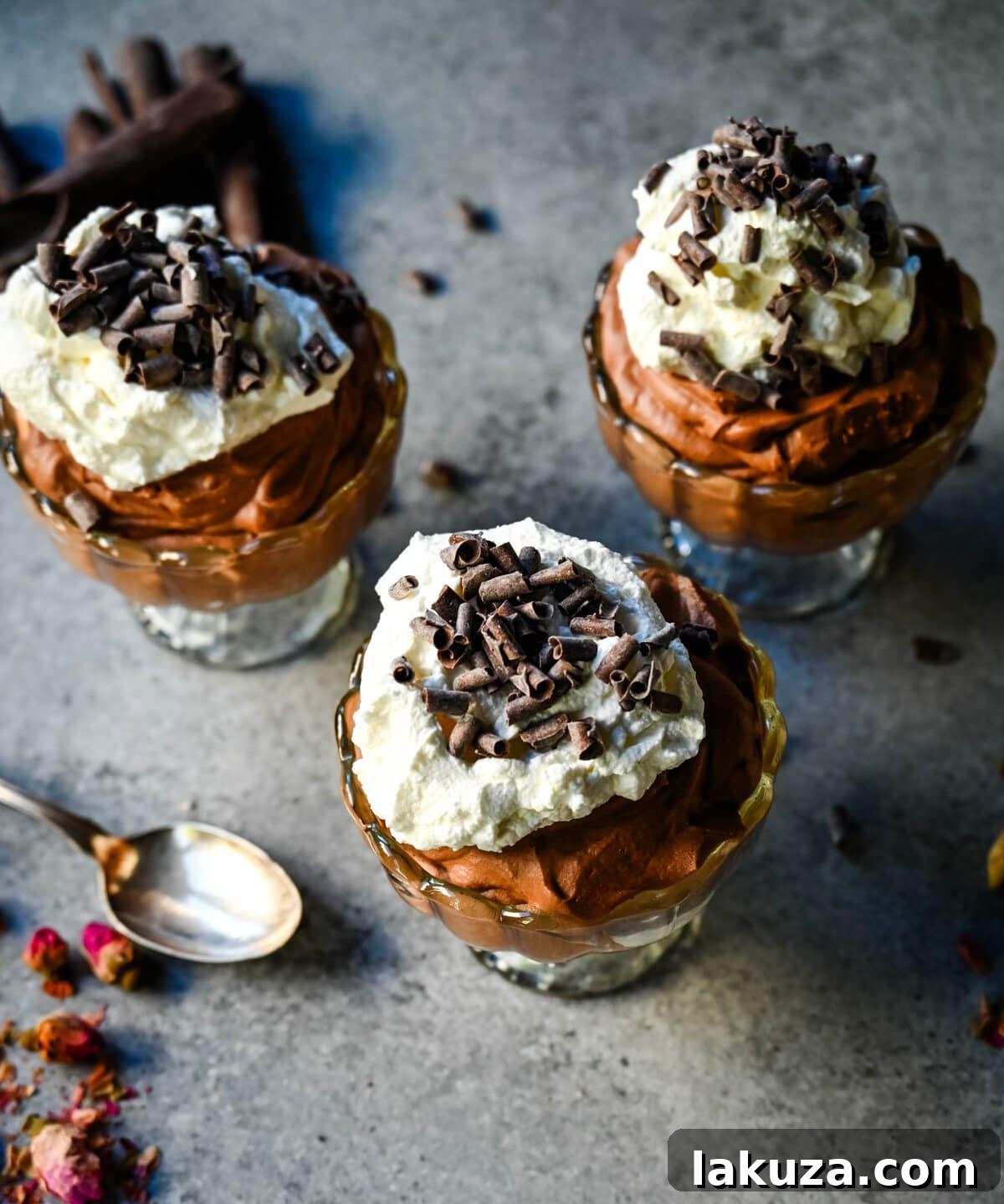 Individual servings of chocolate mousse with a generous dollop of whipped cream and a sprinkle of cocoa powder, looking ready to serve.