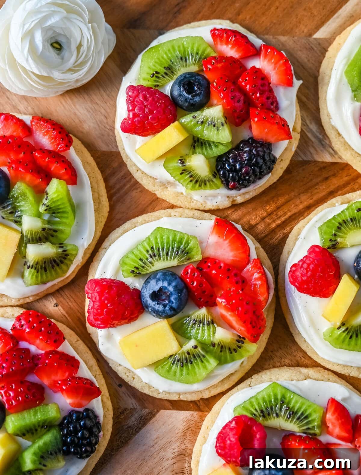 An array of fresh fruits including strawberries, blueberries, kiwi slices, and raspberries, ready for topping fruit pizza cookies.