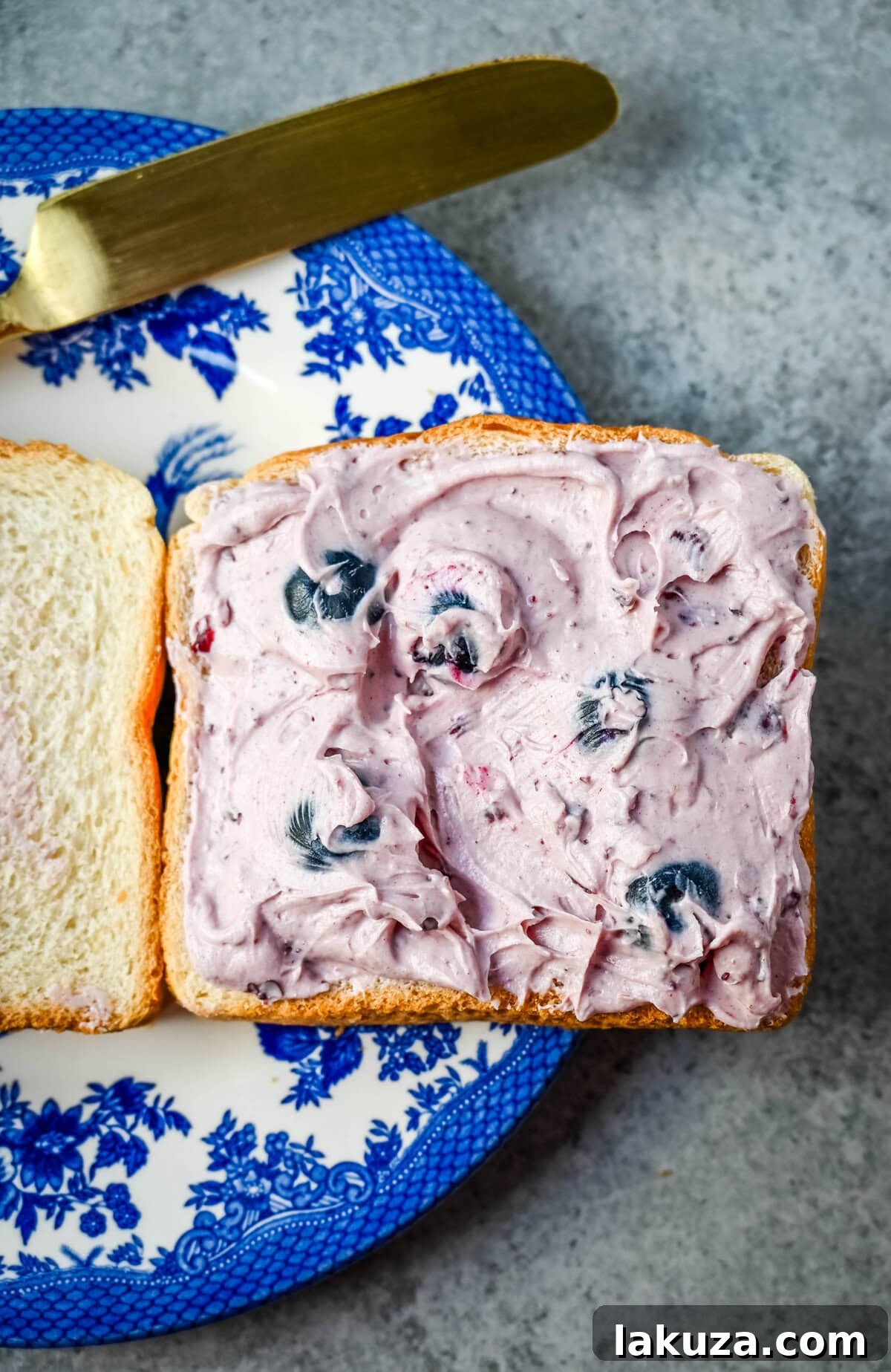 Decadent Blueberry Cheesecake French Toast 6 Spreading the homemade blueberry cream cheese filling onto a slice of thick bread.
