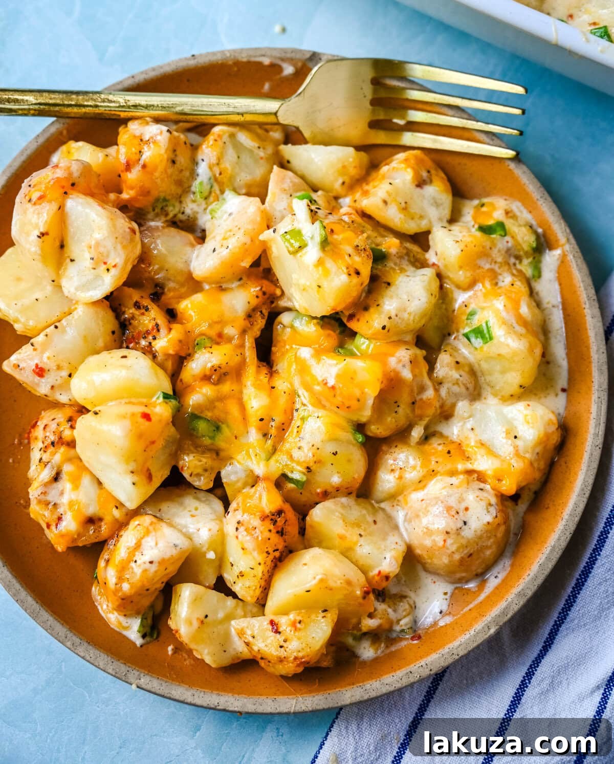 Kerrys Legendary Potatoes 2 A vibrant close-up of Kerry's Special Creamy Potatoes, perfectly golden brown and garnished with fresh green onions, ready to be served from a white baking dish.