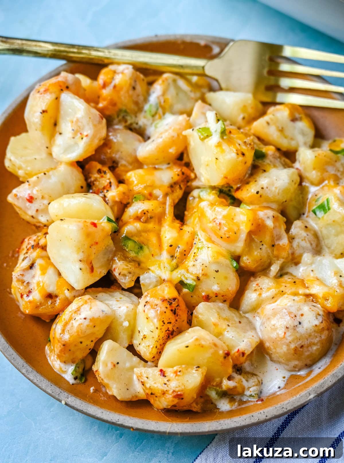 Kerrys Legendary Potatoes 5 A serving of Kerry's Special Creamy Potatoes on a white plate, highlighting the rich texture, melted cheese, and fresh green onions, ready to be savored.