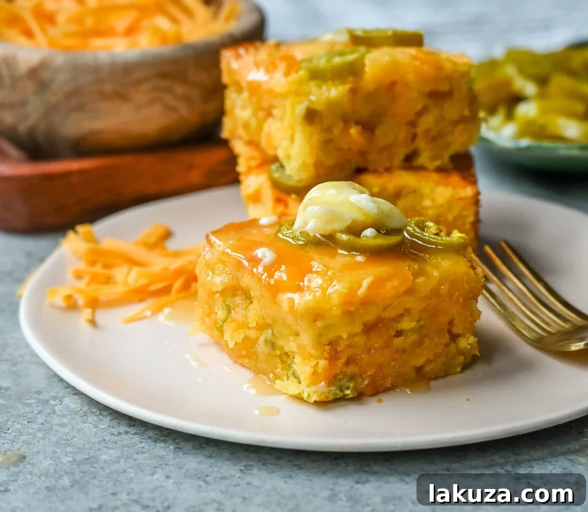 Golden brown homemade jalapeno cheddar cornbread, sliced to reveal a moist, fluffy interior with melted cheddar cheese and green jalapeno pieces.