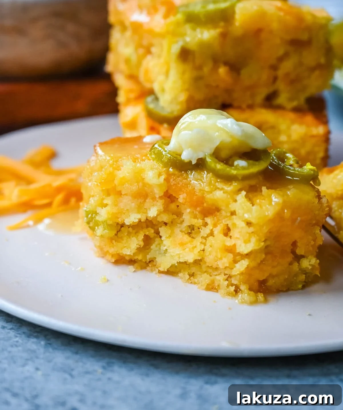 Close-up of baked jalapeno cheddar cornbread, showing the golden crust and visible pieces of melted cheese and green jalapenos.