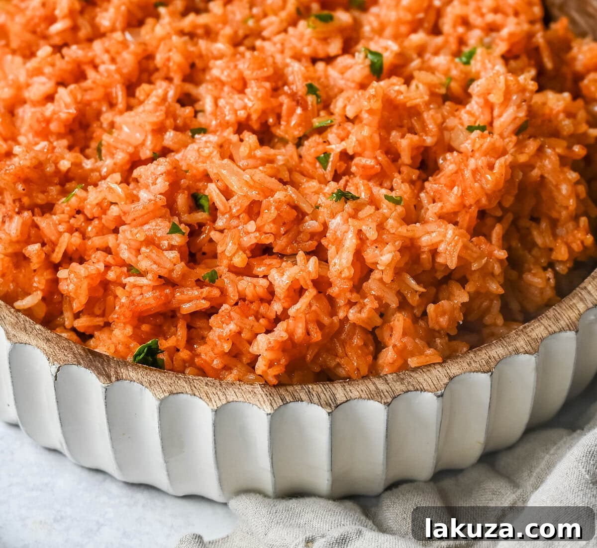 A serving of Spanish Rice in a white bowl, garnished with fresh cilantro and a lime wedge, ready to be enjoyed.