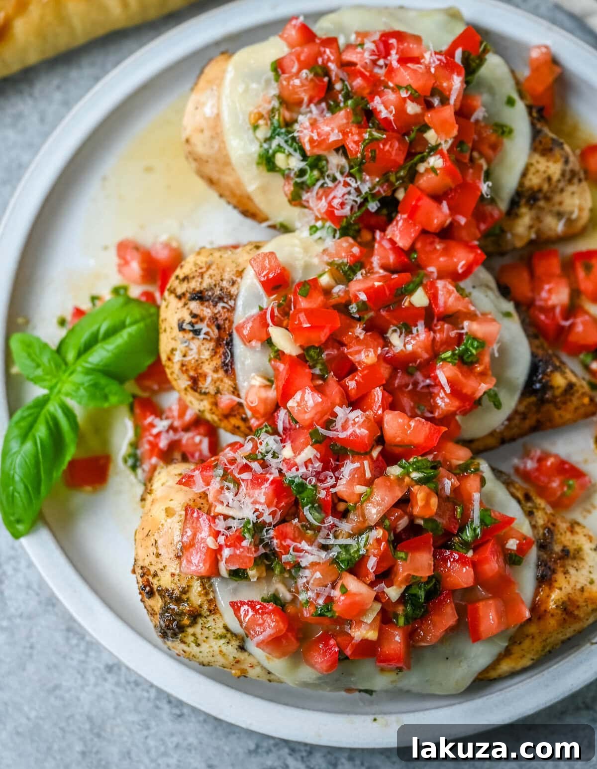 Fresh Bruschetta Chicken 3 Close-up of Bruschetta Grilled Chicken showing melted mozzarella, fresh diced tomatoes, basil, and garlic topping a tender chicken breast.