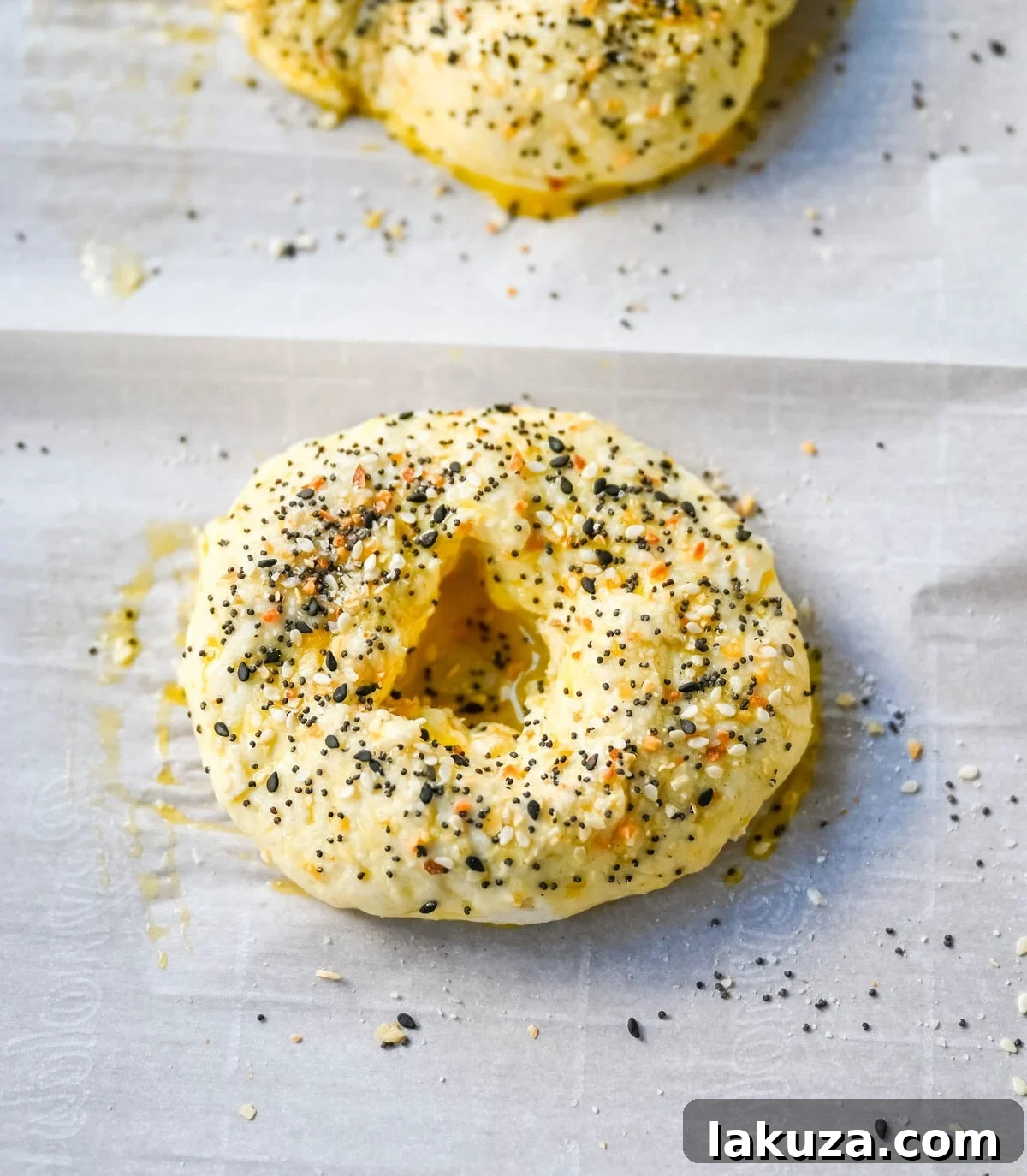 A close up of two baked cottage cheese protein bagels, one with everything bagel seasoning and one with cheddar cheese