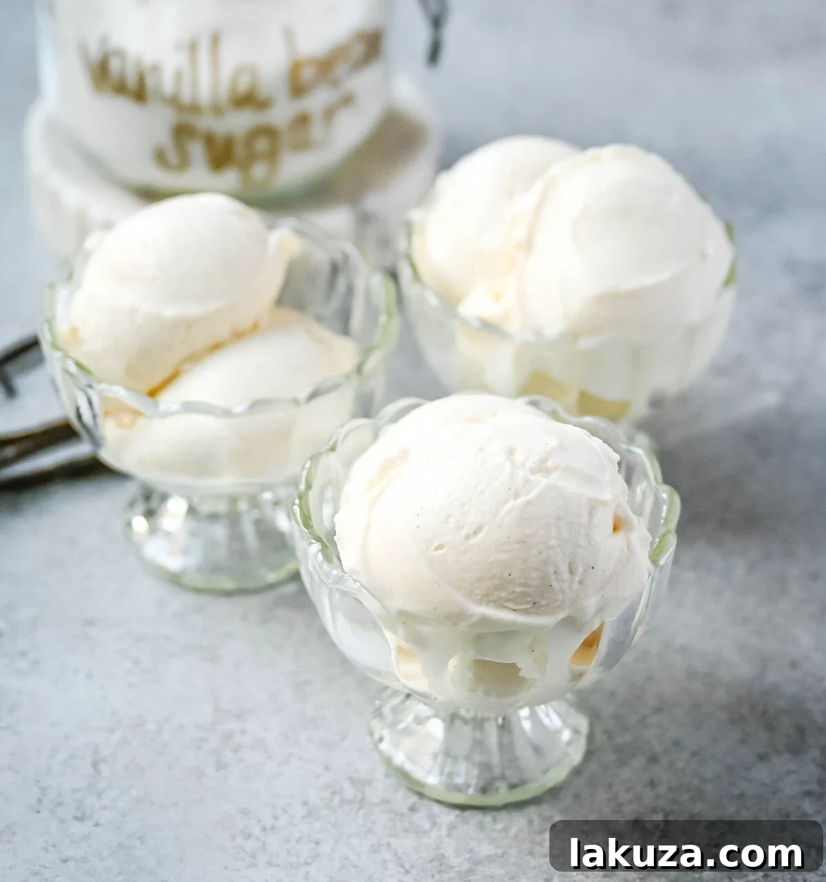 Several scoops of homemade vanilla bean gelato in a glass bowl, garnished with fresh berries and mint, ready to be served.