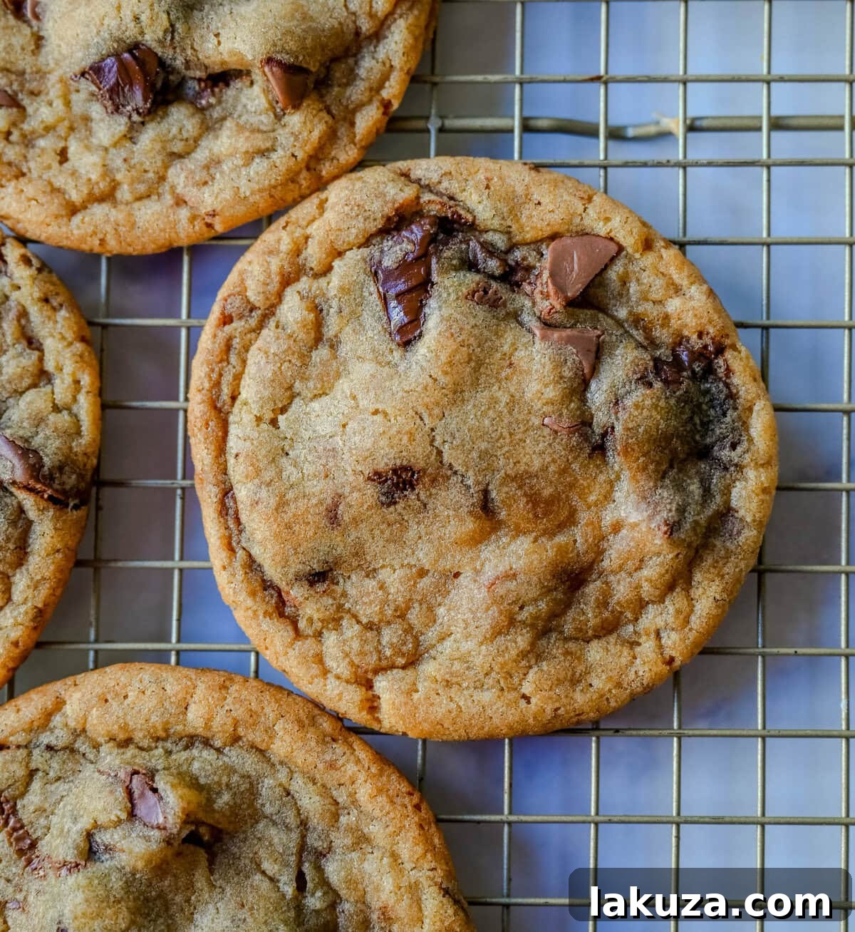 The Ultimate Thin and Chewy Chocolate Chip Cookies 3 A stack of golden, thin chocolate chip cookies with beautifully crinkled tops and visible chocolate puddles, highlighting their soft and chewy texture.