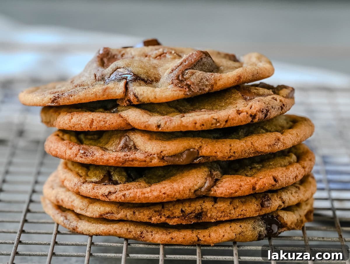 The Ultimate Thin and Chewy Chocolate Chip Cookies 4 A freshly baked thin and chewy chocolate chip cookie, broken in half to reveal its warm, gooey, and perfectly melted chocolate interior, emphasizing its irresistible softness.