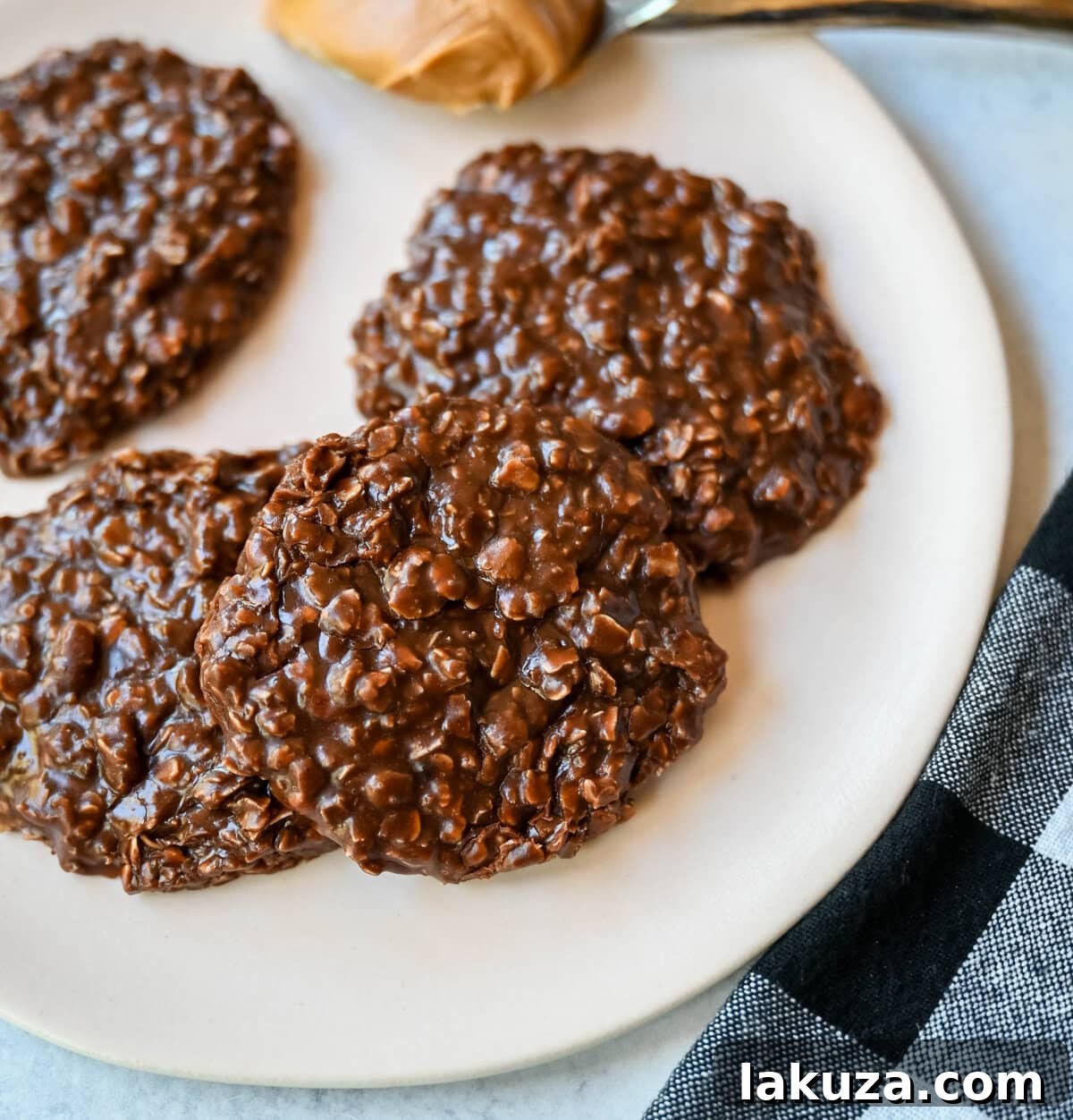 A close-up shot of several perfectly formed, fudgy no-bake chocolate peanut butter oatmeal cookies with visible oats, resting on a cooling rack, ready to be enjoyed.