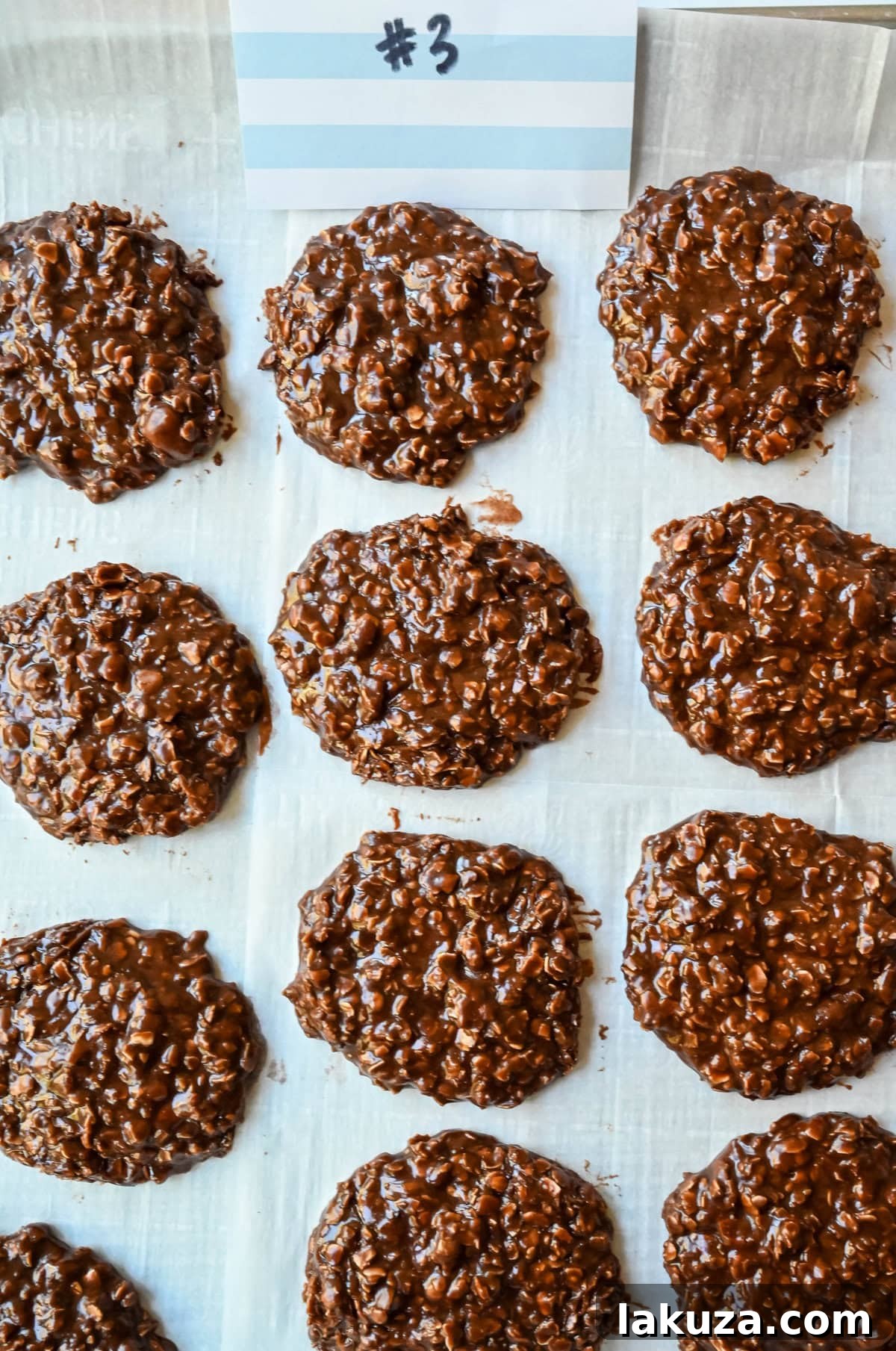 Four distinct batches of no-bake cookies, each with slightly varying textures and colors, laid out on parchment paper for comparison during a recipe testing session.