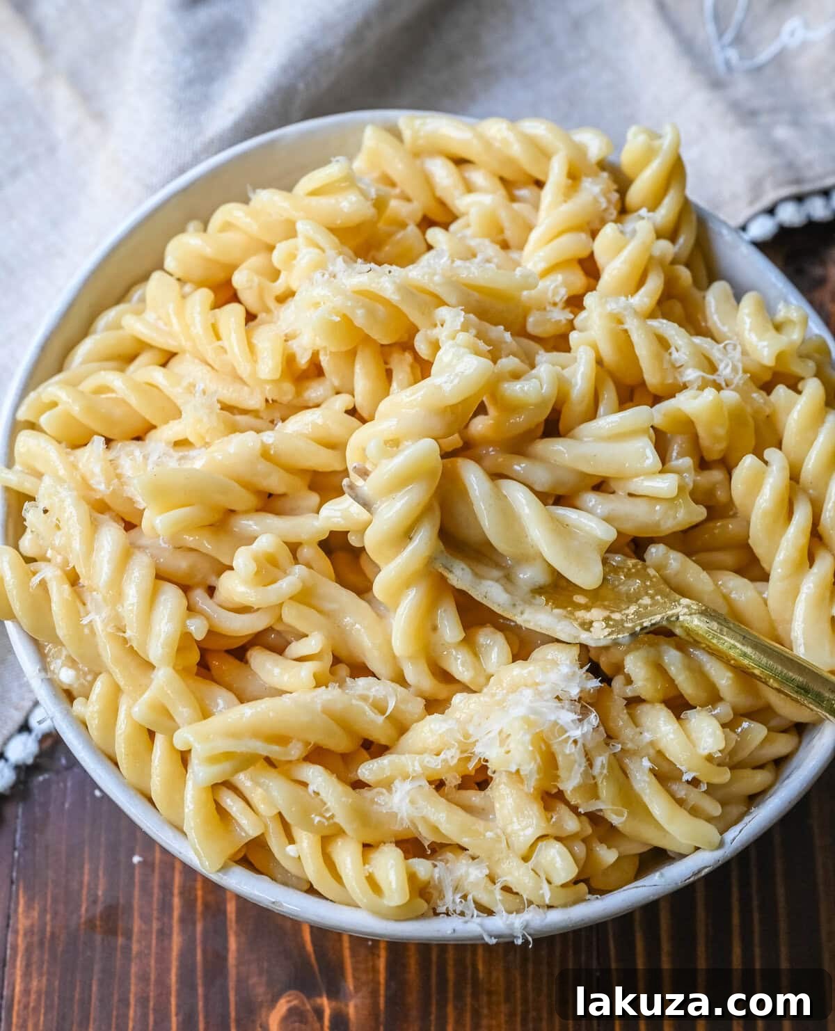 A serving of the world's best buttered noodles, showcasing the tender pasta coated in a rich, creamy butter and parmesan sauce, a testament to its simple yet profound comfort.
