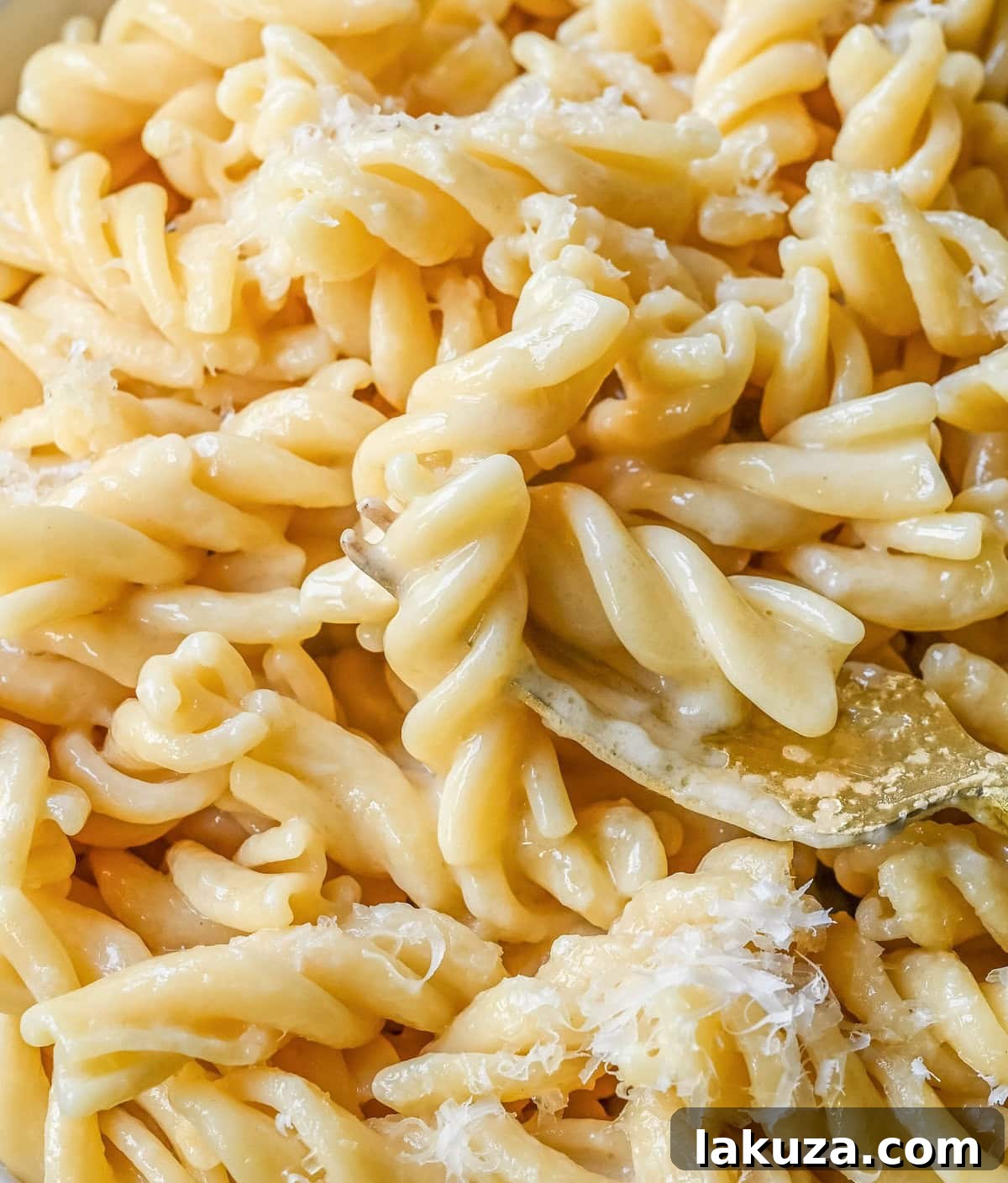 A close-up of a serving of buttered noodles adorned with fresh parsley and a generous sprinkle of grated parmesan cheese, highlighting its creamy texture and inviting appeal.