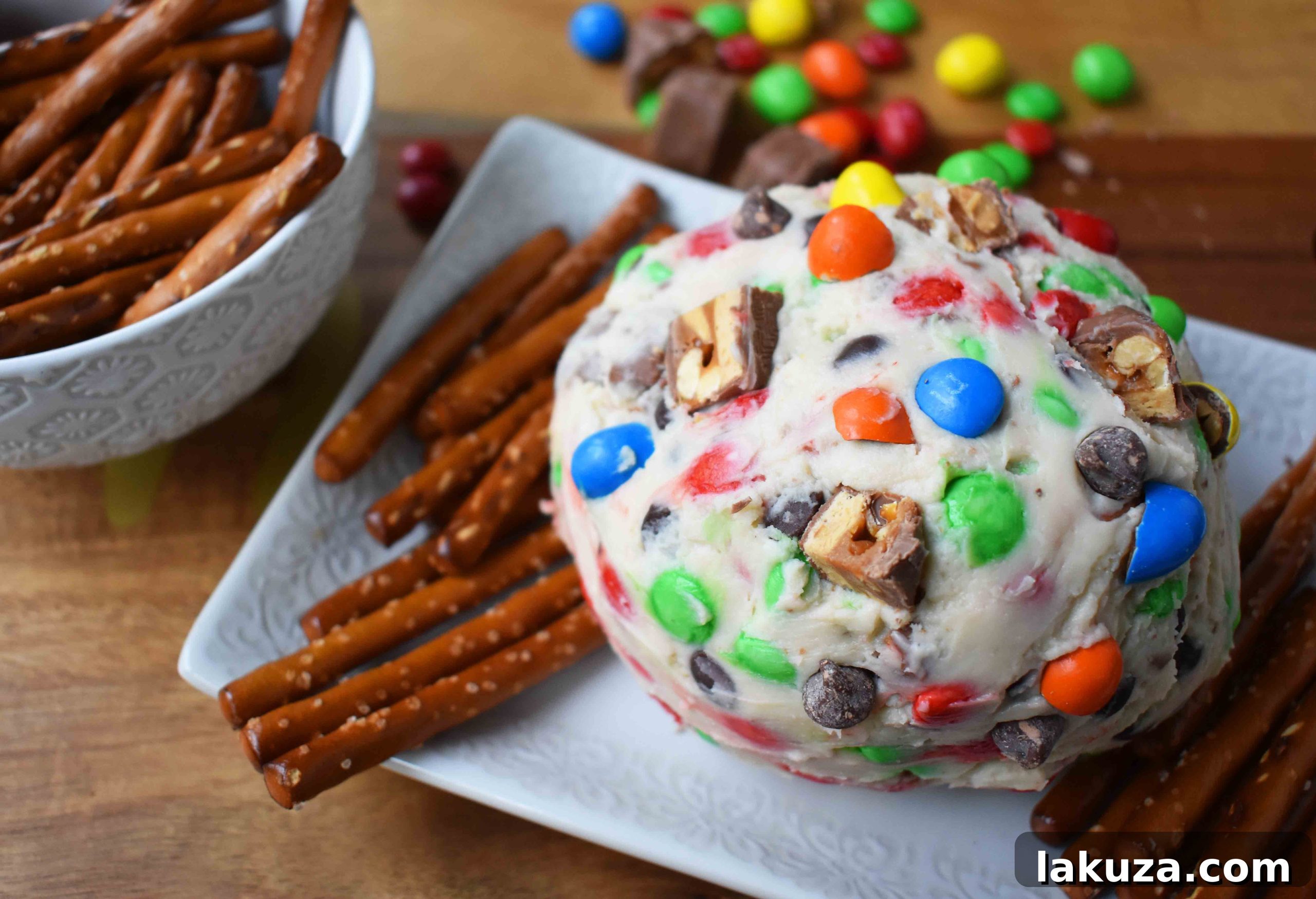 Decadent Candy Bar Cheeseball 4 A beautifully presented Chocolate Candy Bar Cheese Ball on a platter, ready to be served with pretzel dippers.