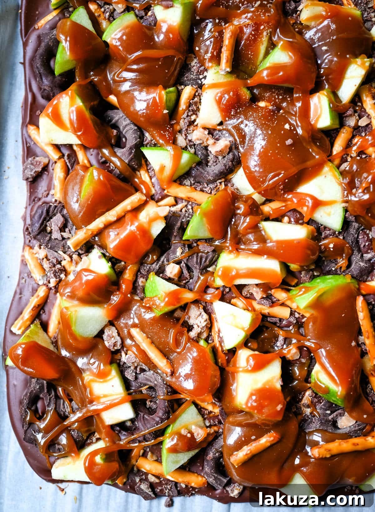 Harvest Spice Caramel Apple Bark 5 A large piece of Caramel Apple Bark, showcasing its rich layers of chocolate, pretzels, diced apples, and caramel, ready to be broken into individual servings.