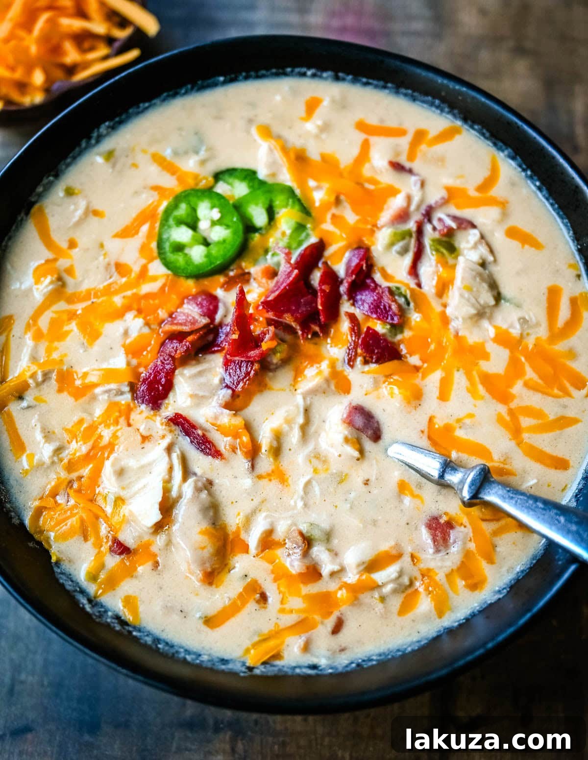 Creamy Jalapeno Chicken Bliss 3 Close-up of creamy chicken jalapeño popper soup with a swirl of cream, crispy bacon bits, and fresh herbs.