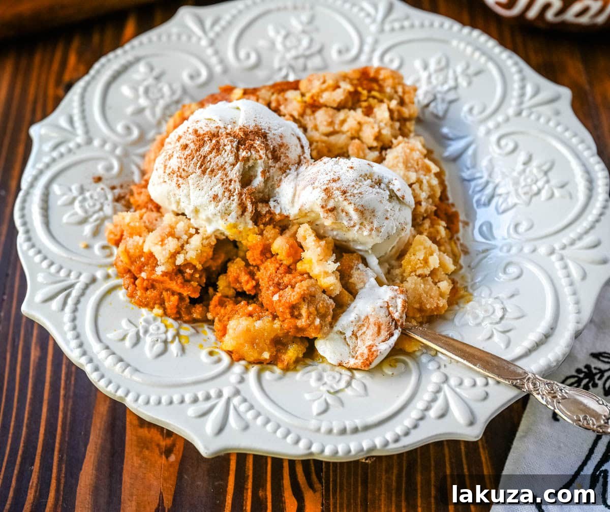 Individual serving of warm pumpkin cobbler topped with a scoop of vanilla ice cream and a sprinkle of cinnamon.