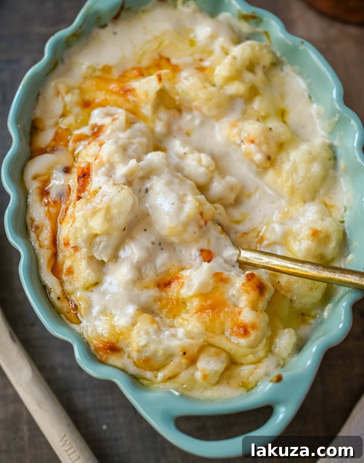 Velvety Cauliflower Bake 5 A serving of creamy cauliflower gratin in a white dish, showcasing its cheesy, golden top and tender florets.