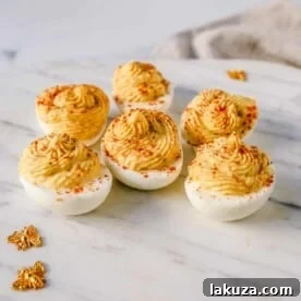 These easy deviled eggs are made with hard-boiled eggs, mayonnaise, mustard, pickle juice, a touch of sugar, a pinch of salt, and pepper, and sprinkled with paprika.
