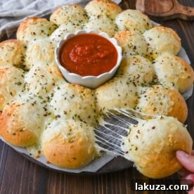 Cheesy garlic monkey bread, or garlic cheese pull-apart bread, made with Rhodes frozen dinner rolls, is soft, buttery, and cheesy. Each roll is dipped in garlic butter and then topped with gooey, melted mozzarella cheese that bubbles as it bakes. The result is a pull-apart bread that's golden on the outside, fluffy on the inside, and has cheesy, garlicky goodness in every bite.