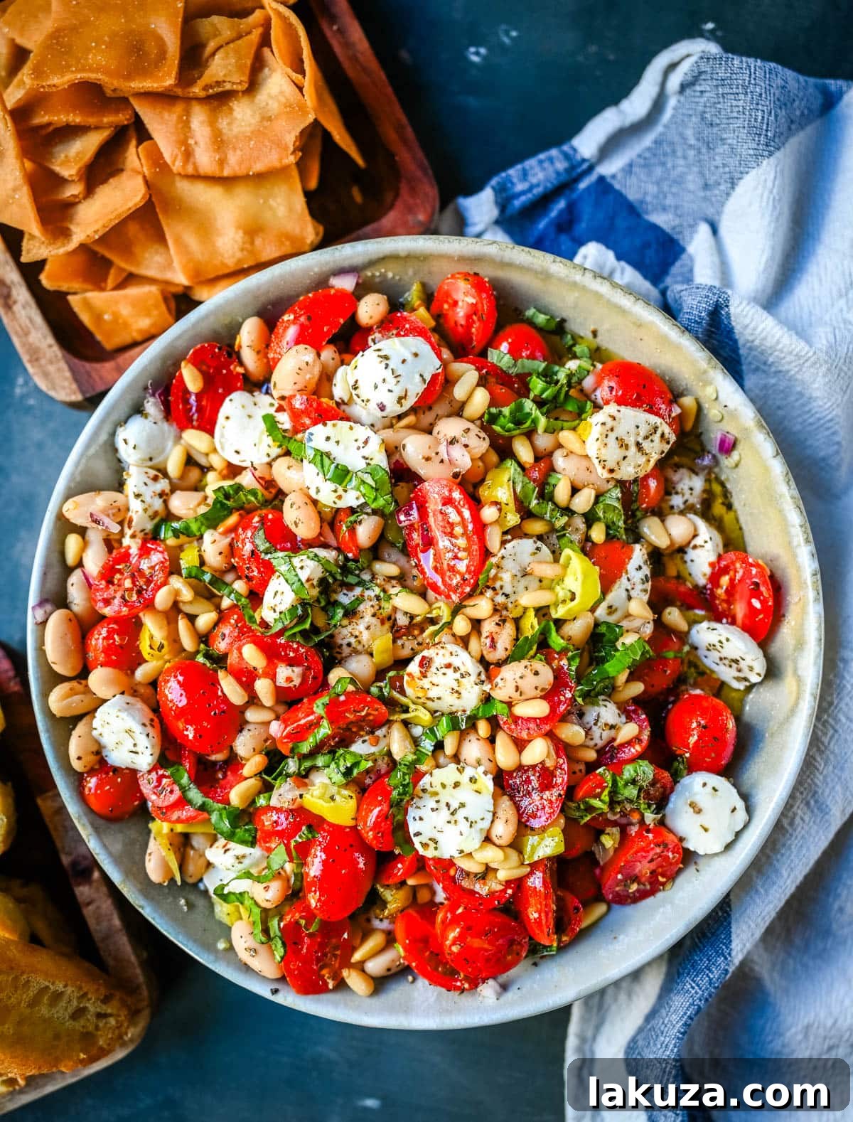 A vibrant bowl of Italian Cowboy Caviar, a fresh Mediterranean dip with tomatoes, mozzarella, white beans, and basil.